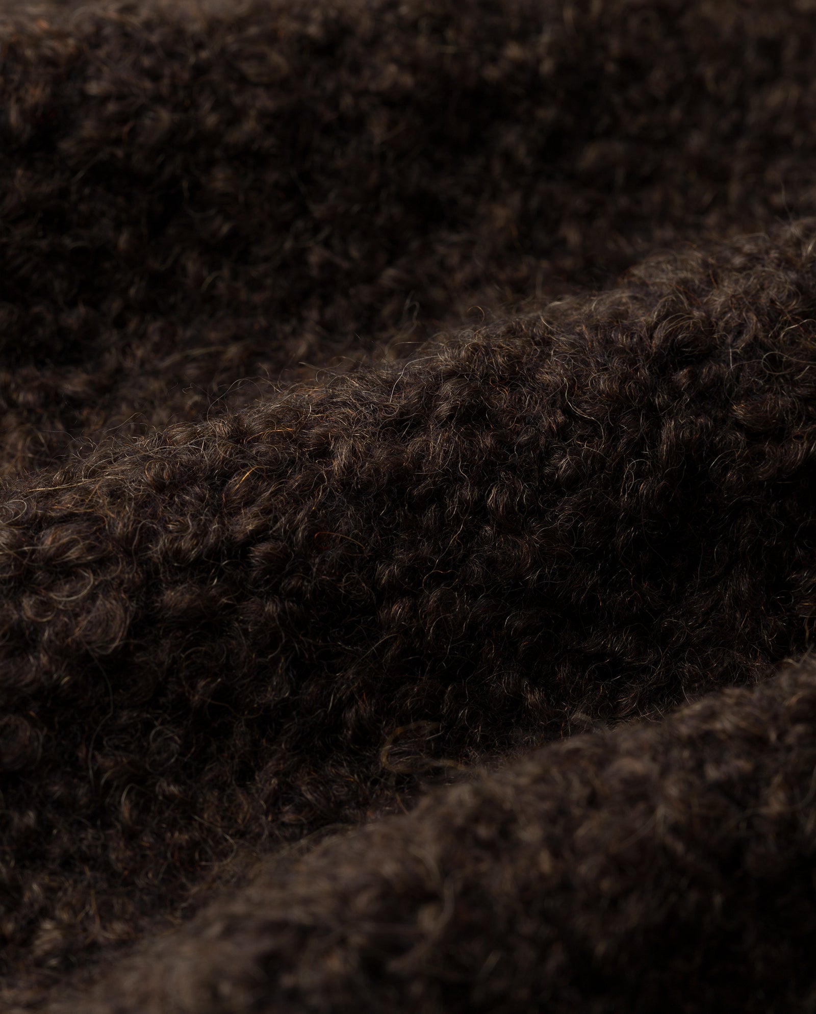 Close-up of dark brown, textured curly wool fabric with soft fibers and wavy surface, crafted from ultra-soft bouclé yarn—ideal for the IVY OAK KRISTAL Cardigan, giving it a casual modern look.