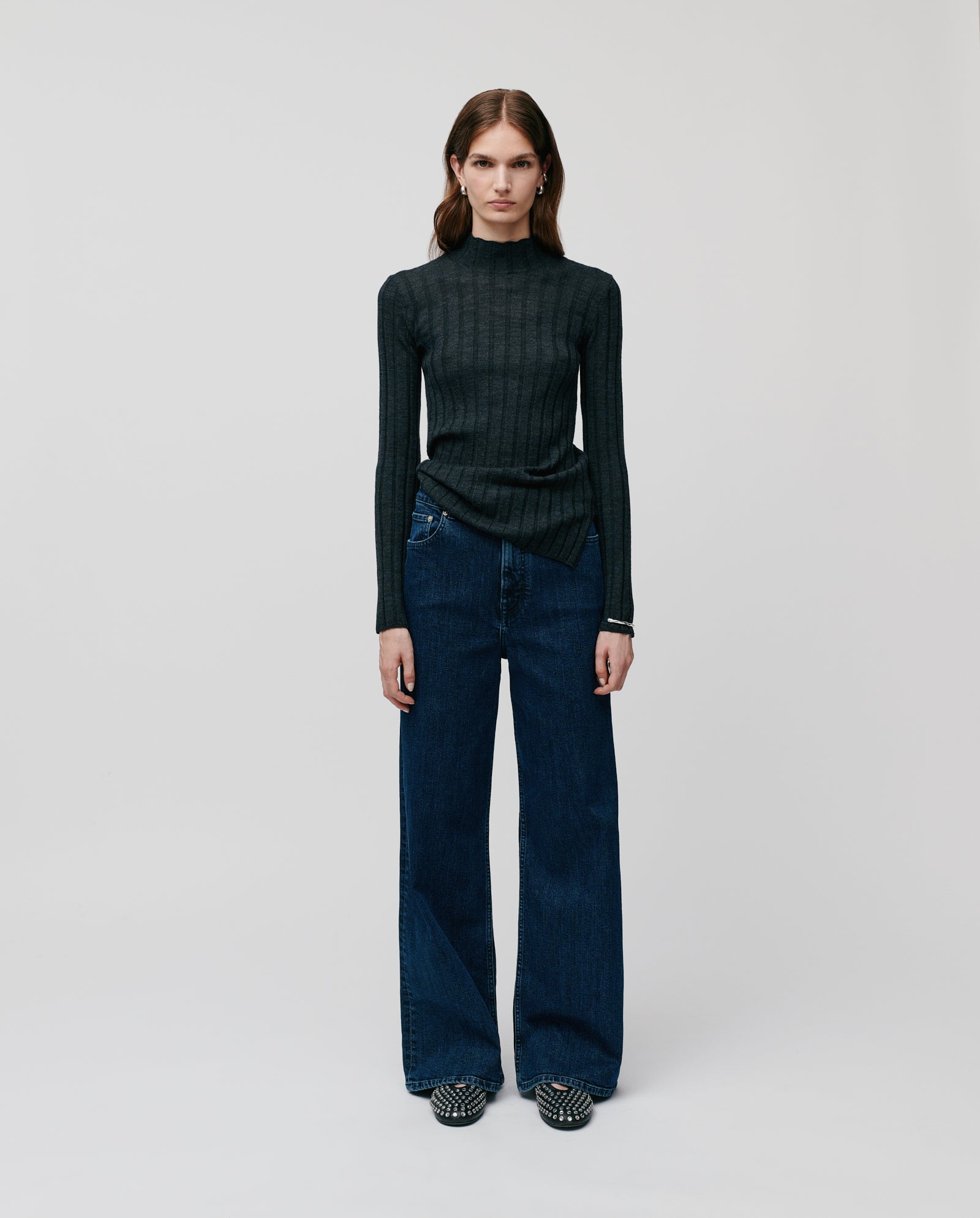 Woman wearing wide-leg jeans, patterned shoes, and the IVY OAK KACY ROSE Jumper—a fitted merino wool sweater with a ribbed structure—standing on a plain white background.