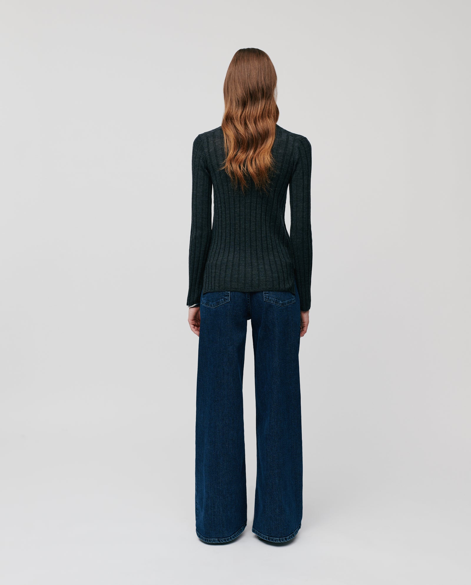 Woman with long wavy hair, back facing the camera, wears the IVY OAK KACY ROSE Jumper paired with wide-leg jeans.