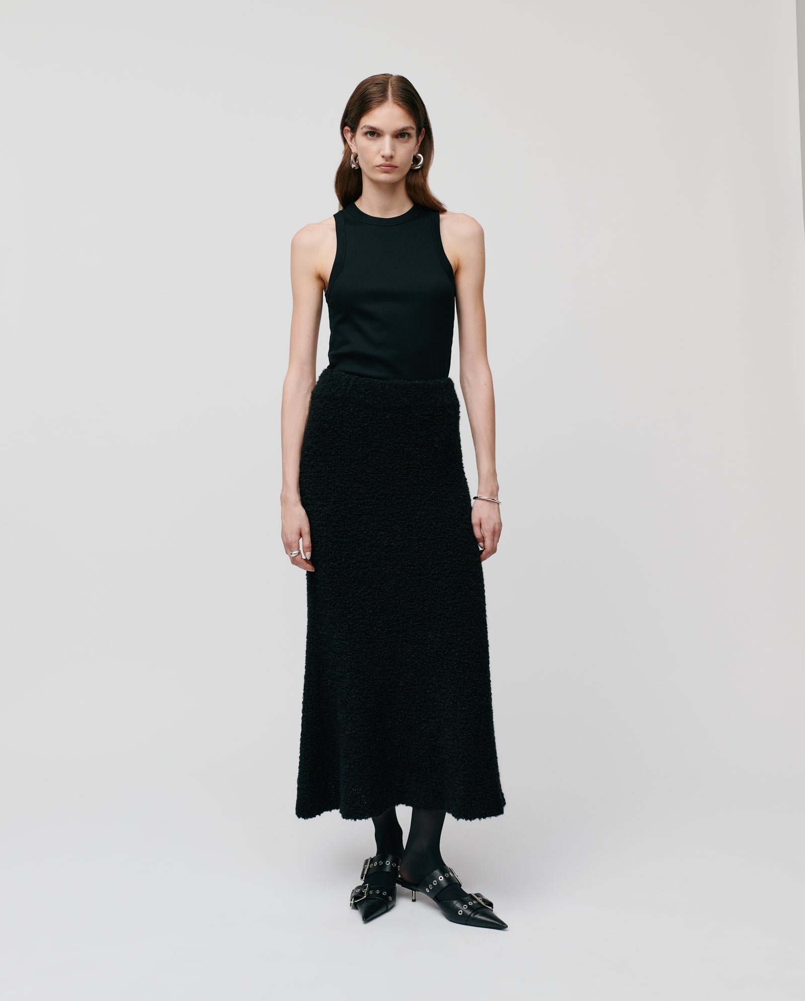 A woman in a black sleeveless top and the IVY OAK KRISTYN Skirt, featuring an A-line silhouette and elastic waistband, stands against a plain light background.