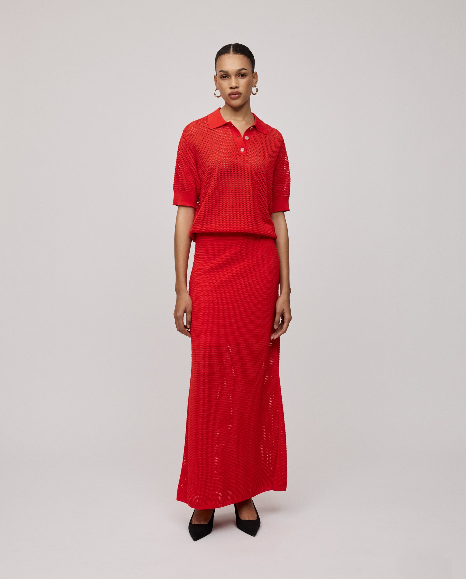Woman wearing the IVY OAK FLO Top, a red short-sleeved summer top, paired with a long skirt and standing against a plain light background.