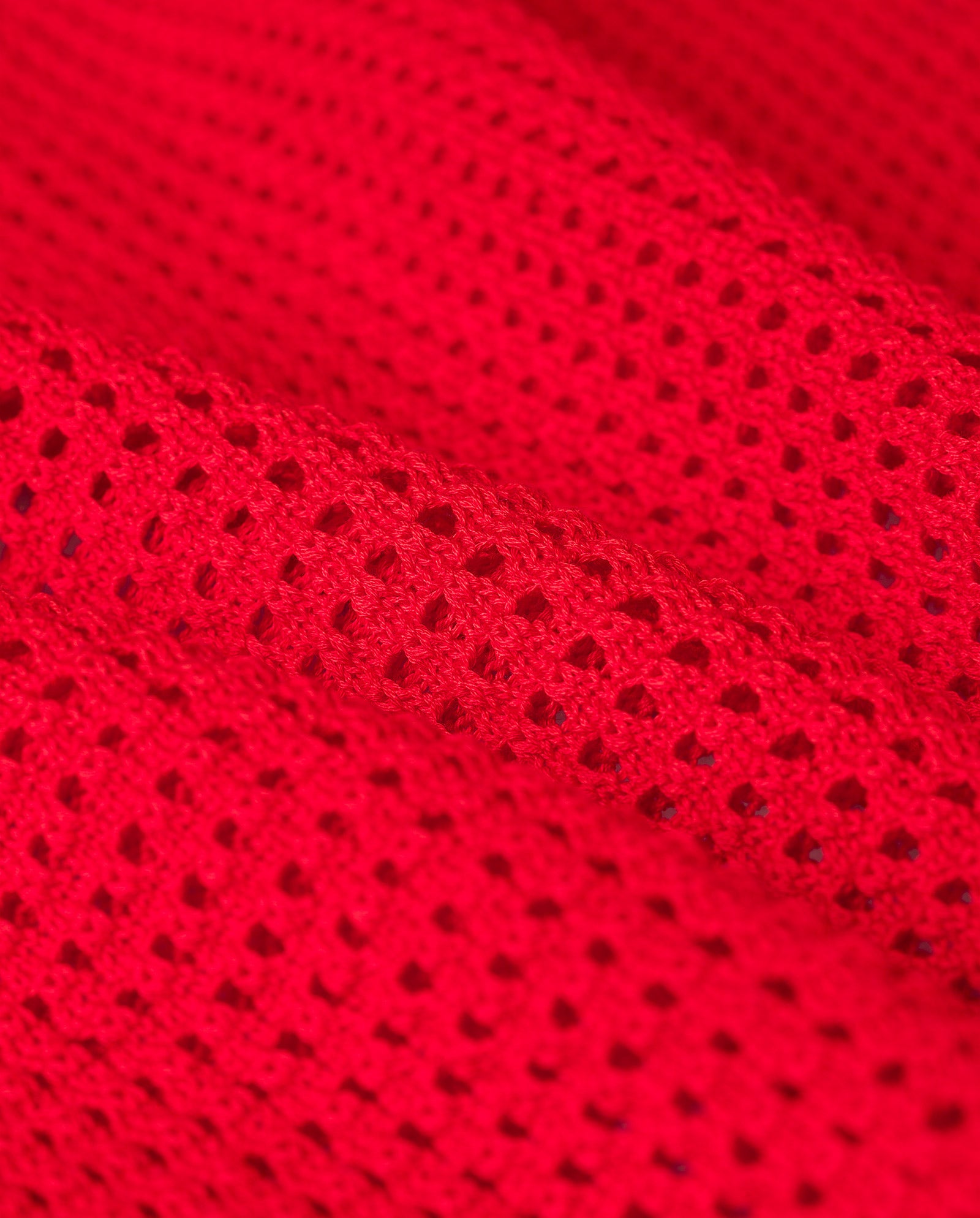 Close-up of the FLO Top by IVY OAK, featuring bright red mesh fabric with small, evenly spaced holes and an open knit design for a light, breezy summer vibe.