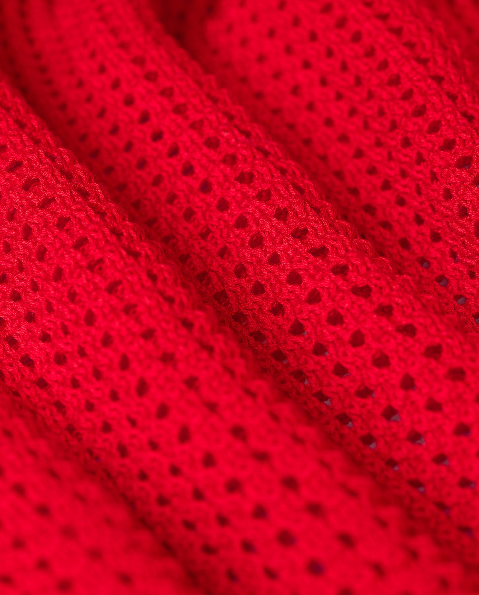 Close-up of vibrant red open knit fabric with a textured, airy pattern—perfect for crafting the light A-line silhouette of the IVY OAK FABRIZIA Skirt.