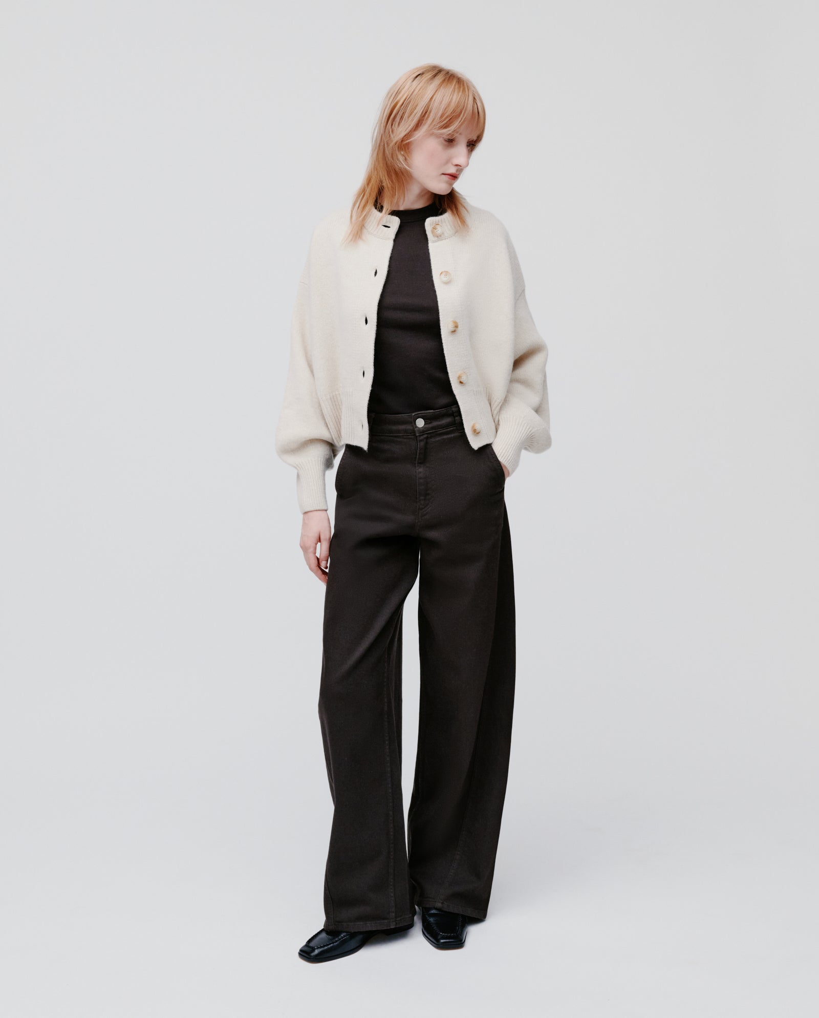 A person wears the IVY OAK KARMA Cardigan with wide sleeves, paired with a black top, wide-leg black pants, and black shoes, standing against a plain background.