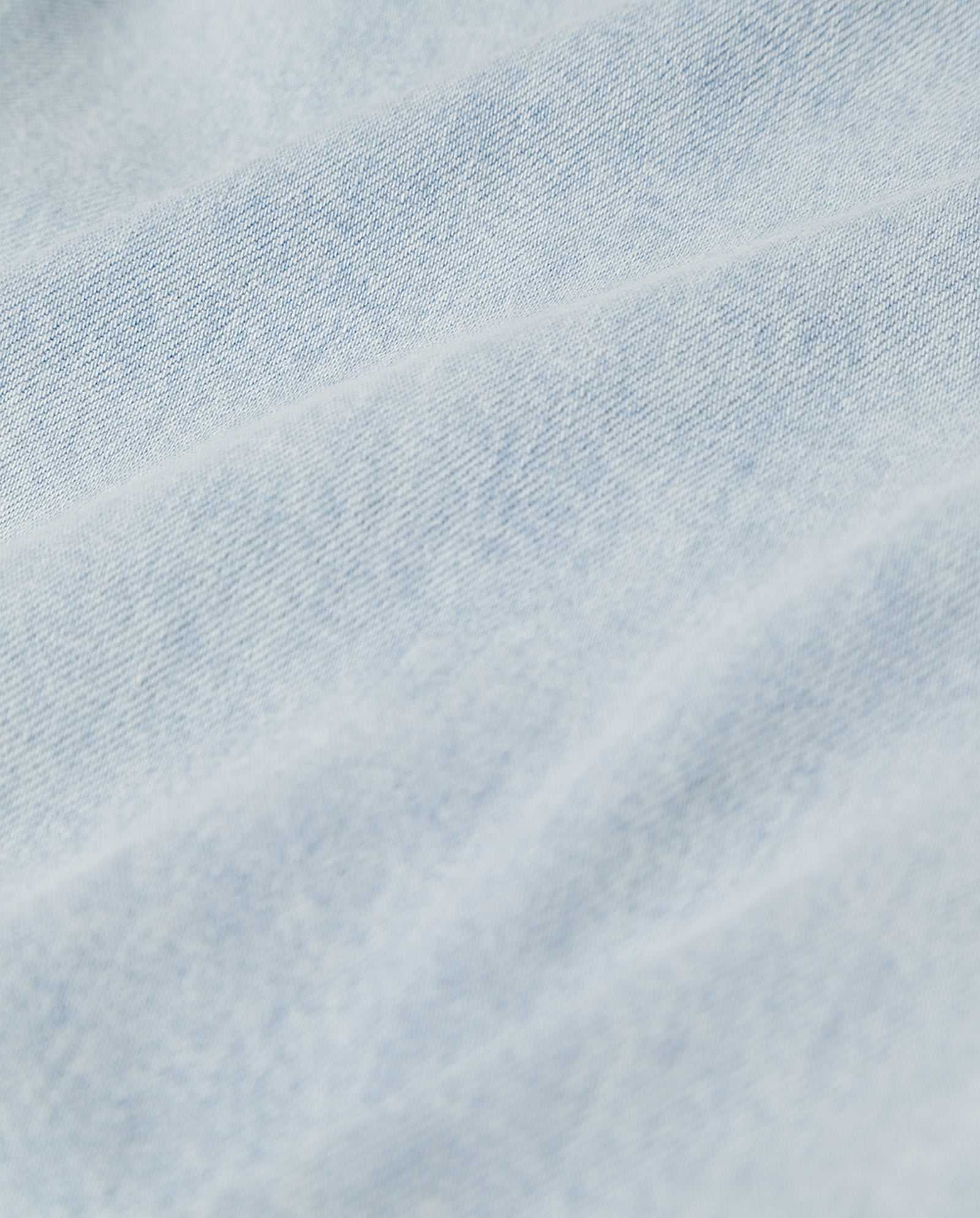 Close-up of light blue denim fabric with soft folds and visible texture, evoking the signature wide legs and patched pockets of IVY OAK’s PIXIE Trousers.