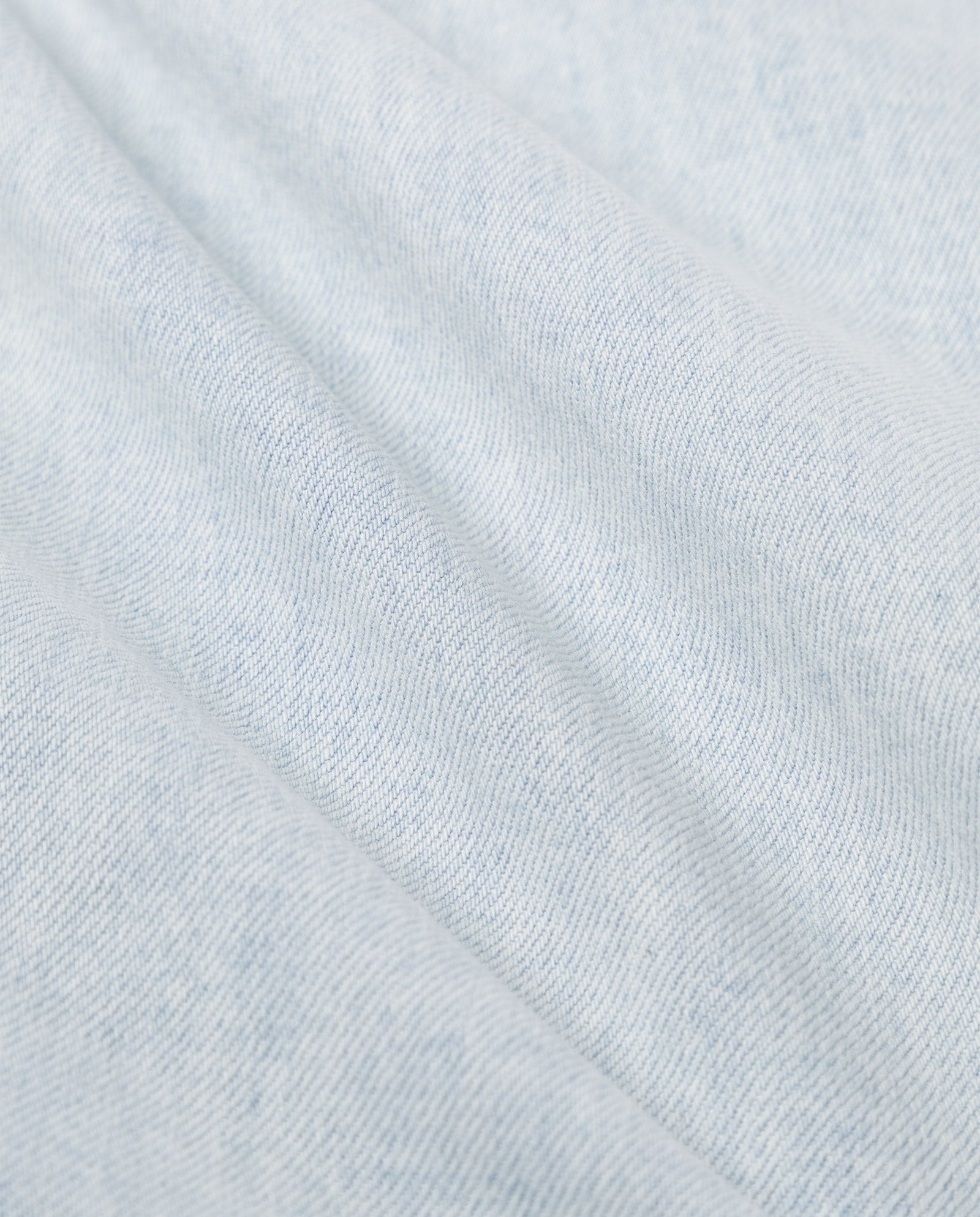 Close-up of light blue denim with soft folds and subtle texture, perfect for IVY OAK’s PETRA Trousers in a stylish barrel-leg design.