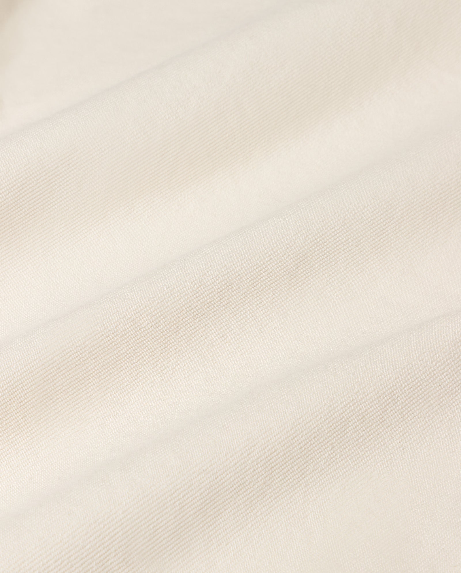 Close-up of the soft, off-white fabric of IVY OAK’s PETRA Trousers, showing its textured surface and gentle folds, similar to material used in stretchy jeans.