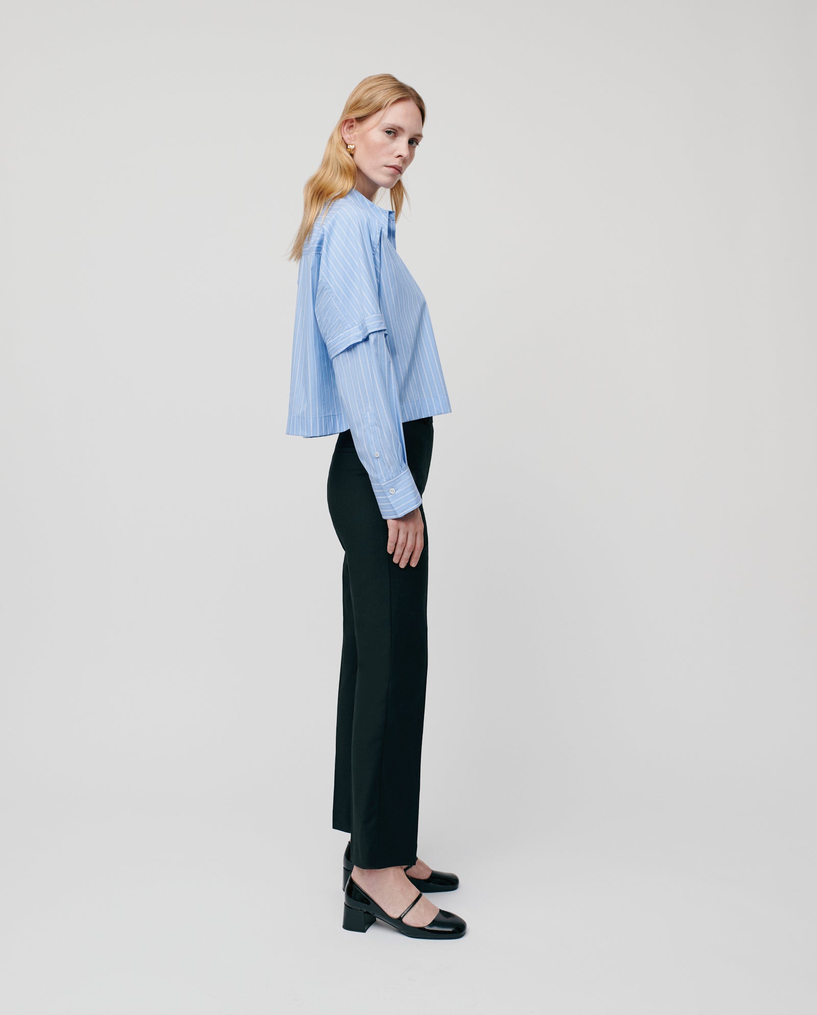 A woman in a blue striped shirt and IVY OAK POLINA Trouser stands sideways against a plain white background.