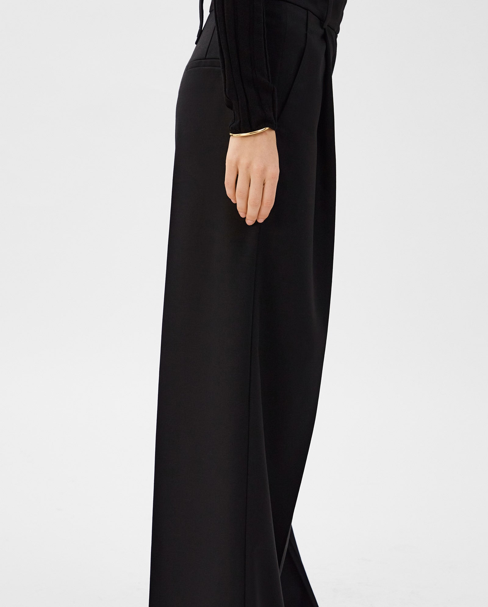 Model shown from waist down in a side view wearing IVY OAK PRESCILLIA black wide leg trousers and a long-sleeve black top.