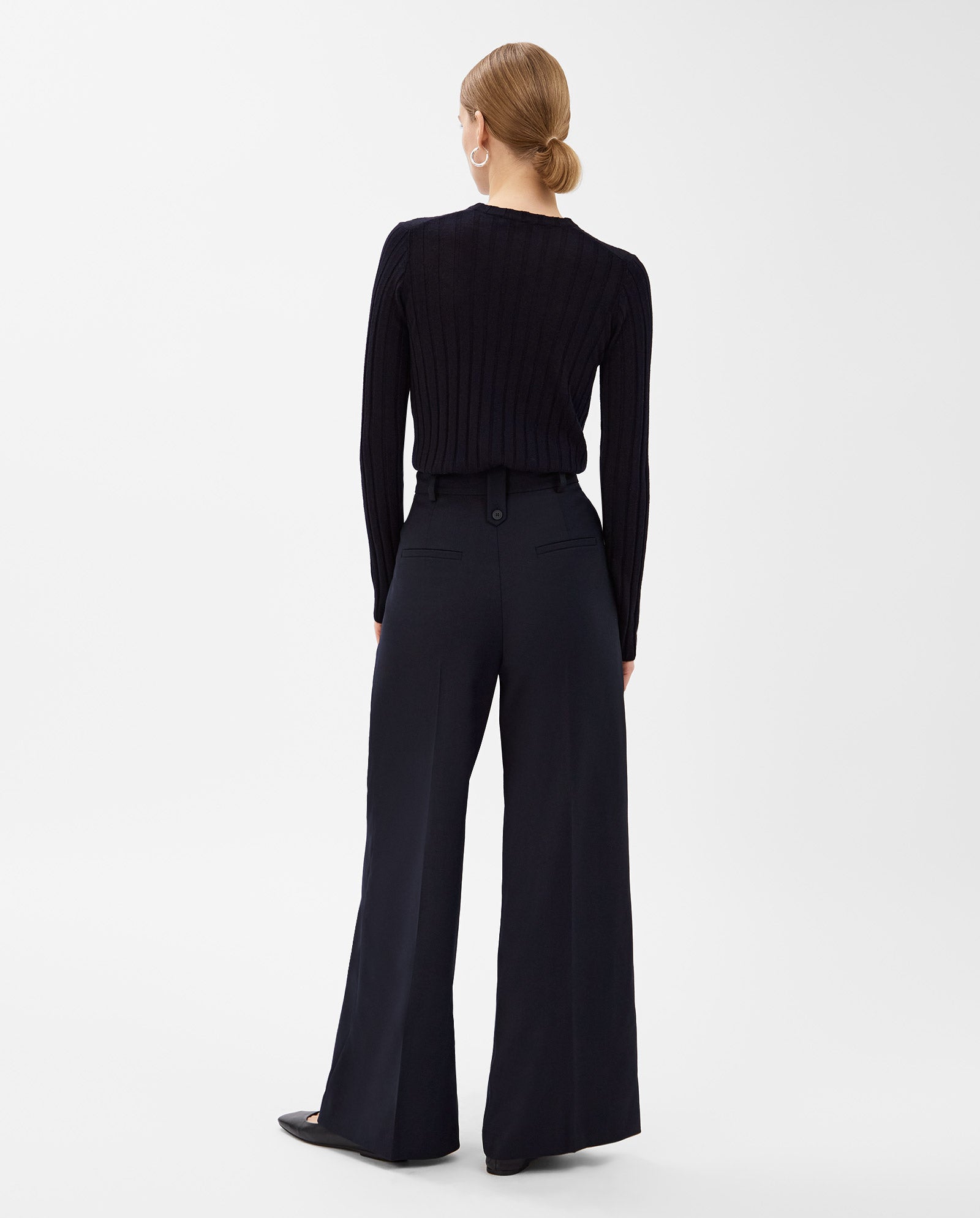 Woman with blonde hair in a low bun, seen from the back, wearing a black sweater and IVY OAK PRESCILLIA Trouser.