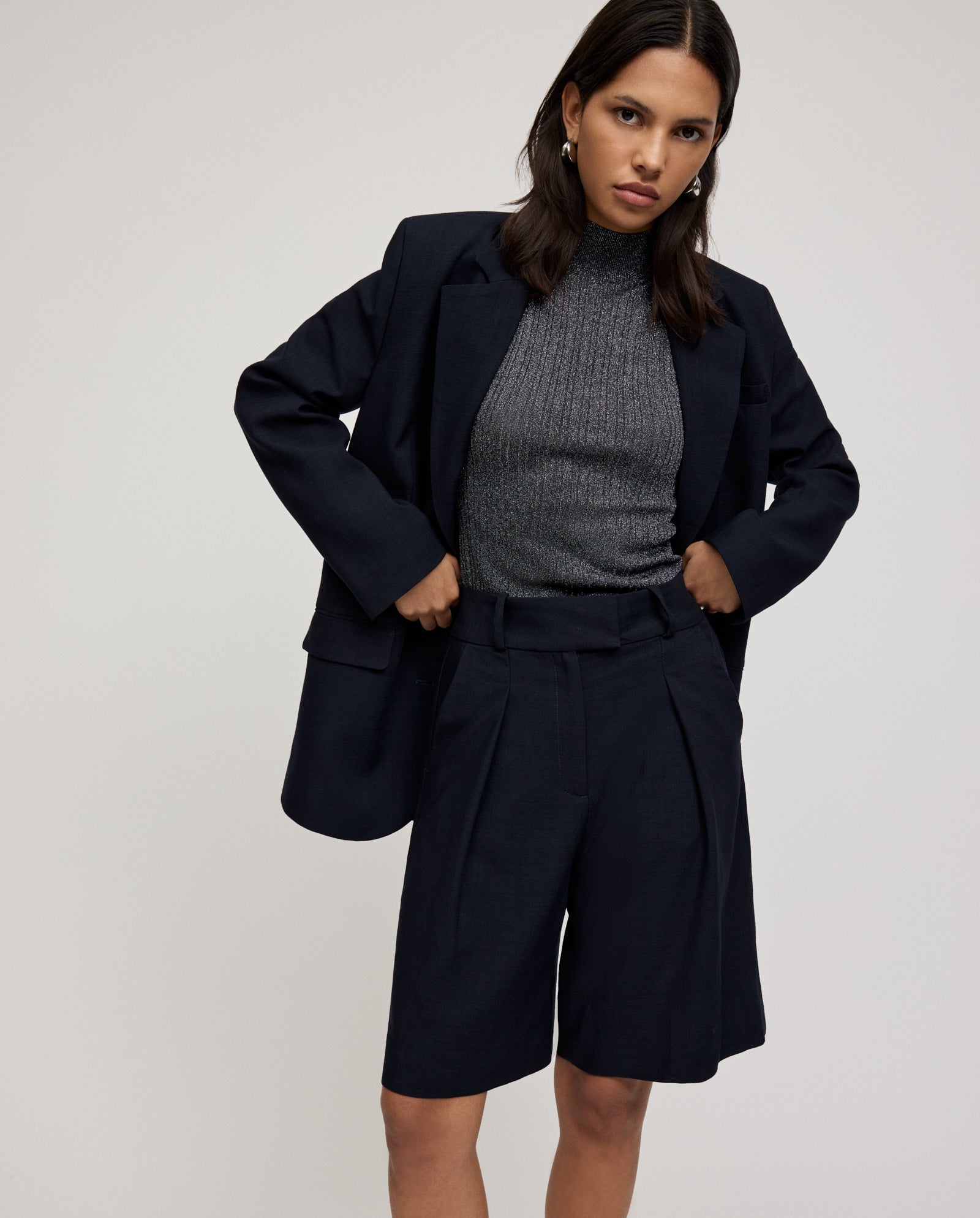 Woman wearing IVY OAK PEONY SUE Trousers with a gray ribbed turtleneck, standing against a neutral background.