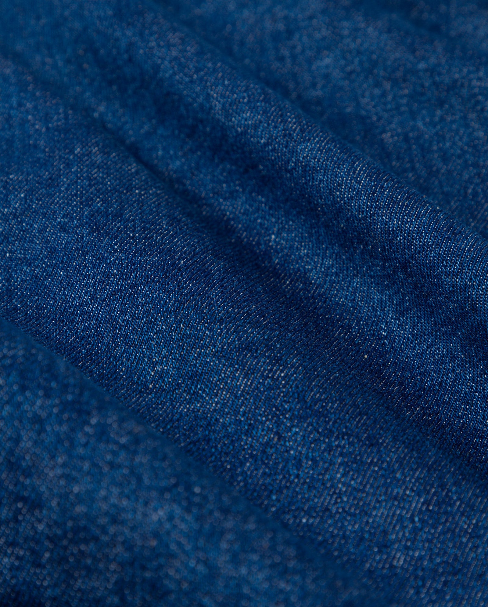 Close-up of blue denim fabric, showcasing the texture, weave pattern, and contrast stitching on IVY OAK’s POEMA Trousers.