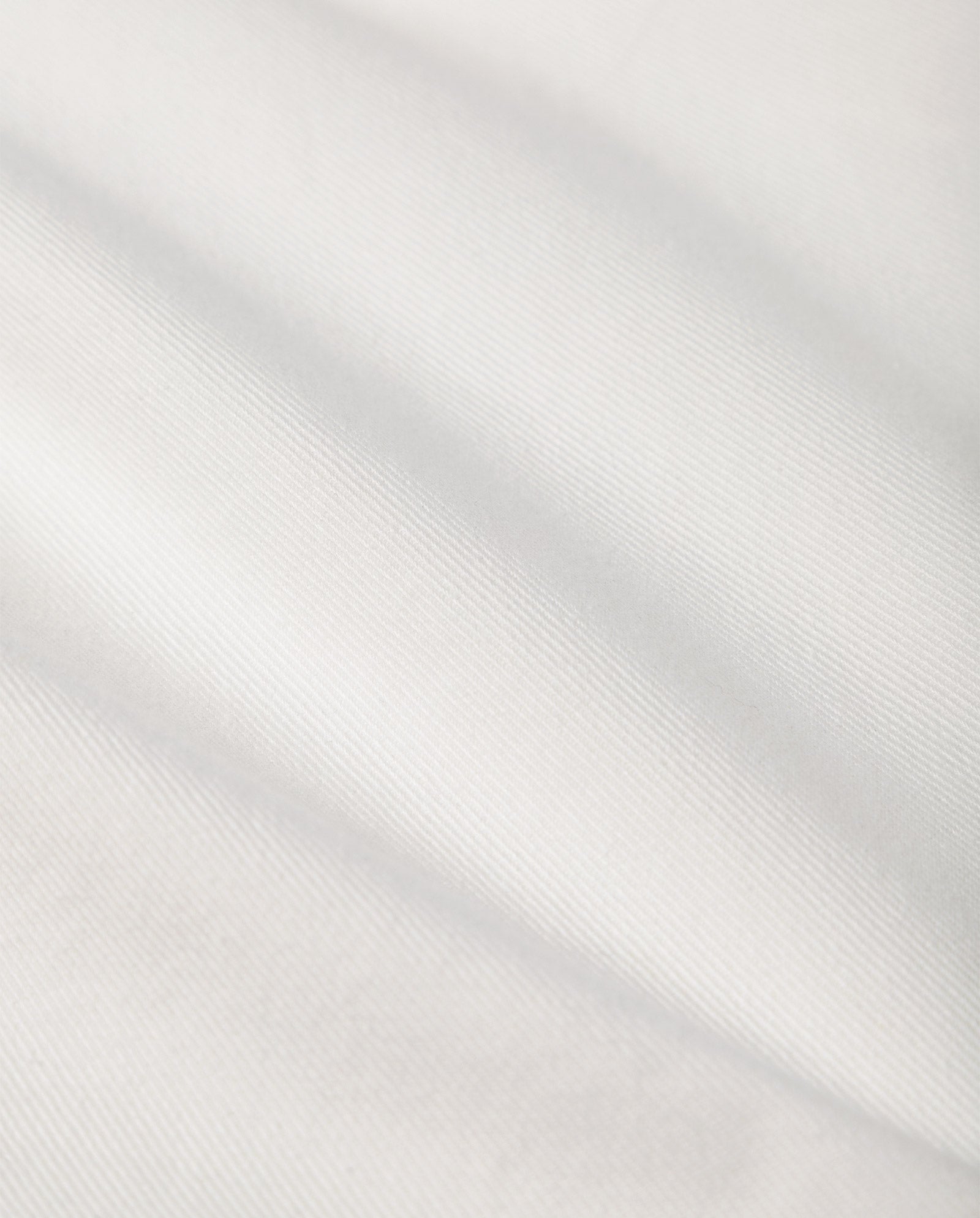 Close-up of white fabric with a subtle diagonal weave pattern and soft folds, reflecting the quality found in IVY OAK’s POEMA Trousers.