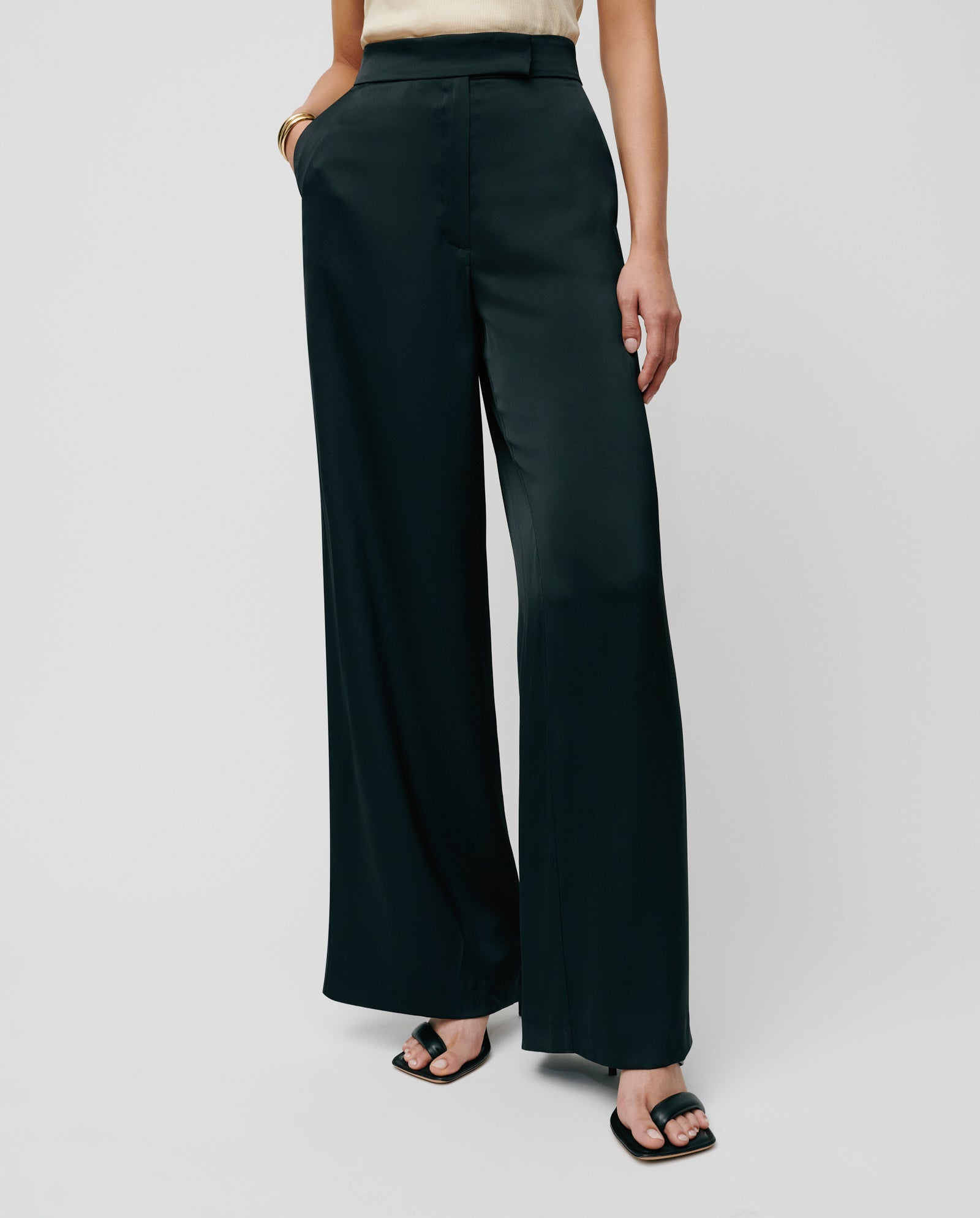 A person wearing high-waisted IVY OAK PRIYA ANN Trousers and black sandals stands with hands in pockets.