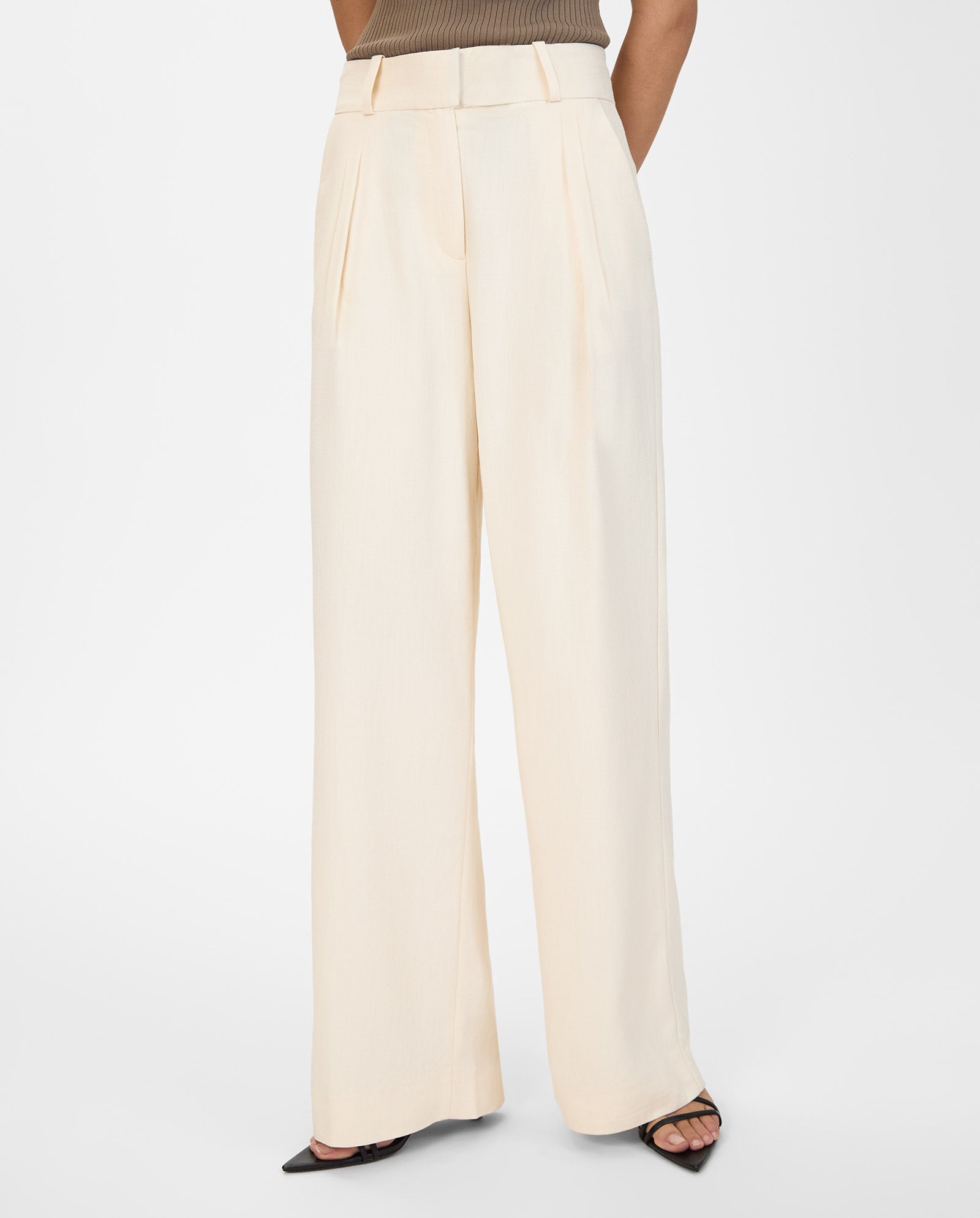 Model wears the PRESCILLIA ANN high-waisted, pleated wide leg trousers in cream by IVY OAK, styled with black open-toe heels against a white background.
