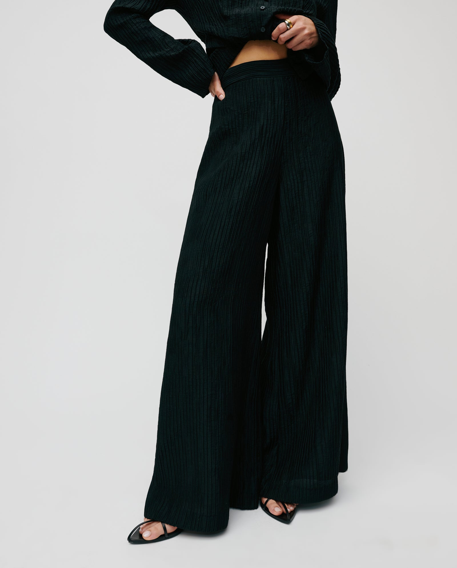 A person wears IVY OAKs PORTIA Trouser in black viscose with open-toe heels and a partially visible EVELYN blouse, set against a plain background.