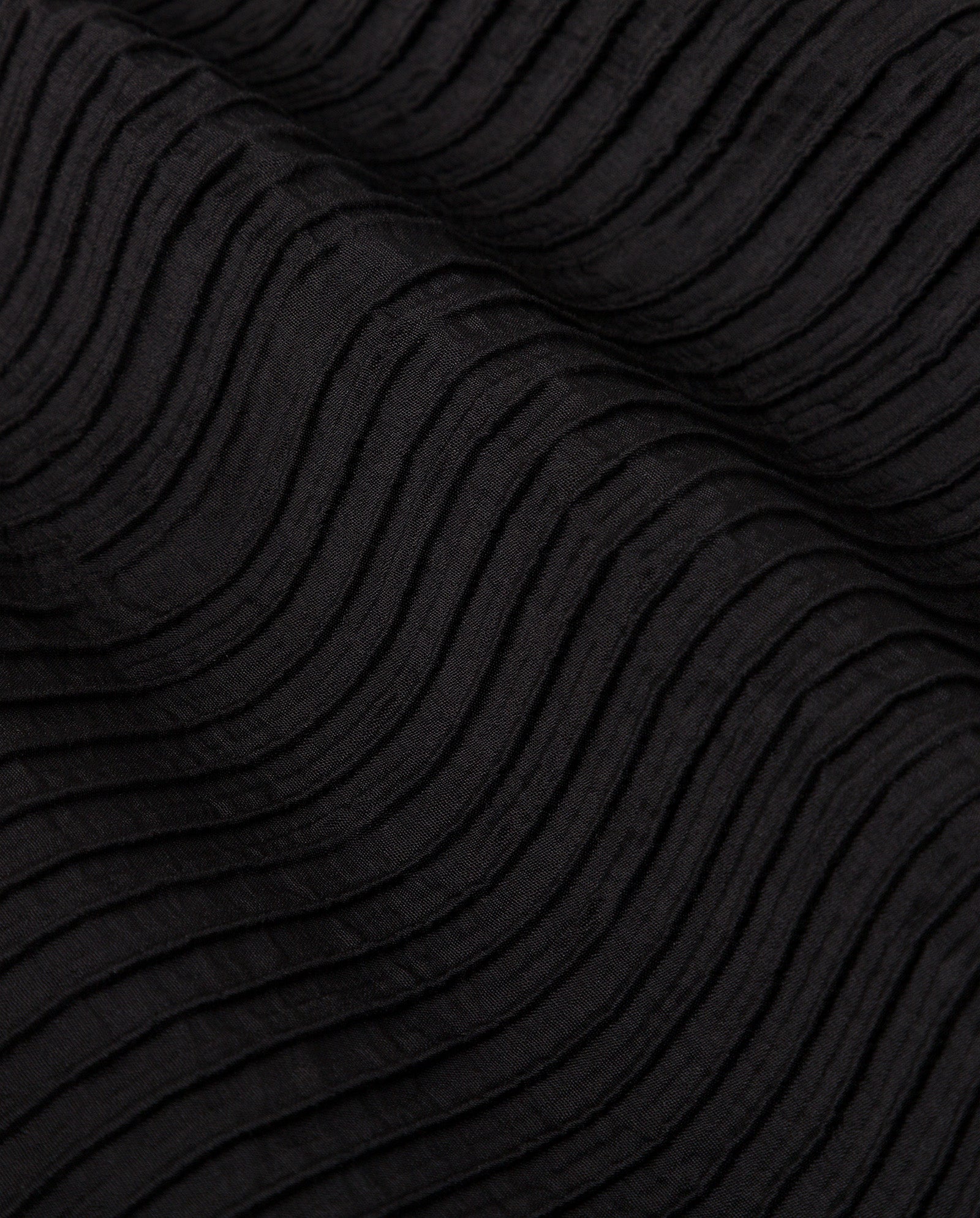 Close-up of black viscose fabric from the EVELYN blouse, featuring wavy, textured raised lines in a ripple pattern—perfectly paired with IVY OAKs PORTIA Trousers.