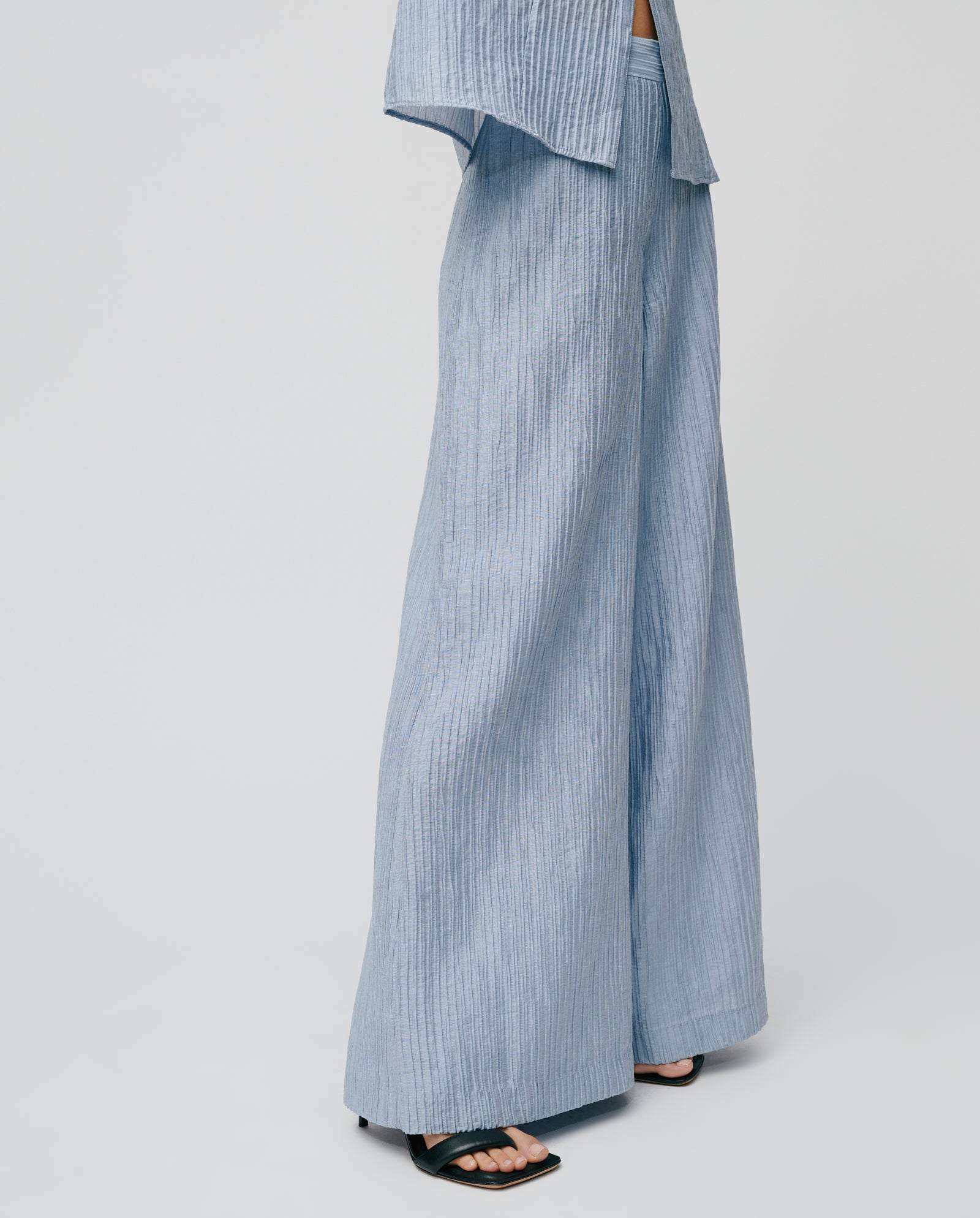 Person wearing IVY OAK’s PORTIA Trouser in light blue viscose with black sandals and a partially visible top, set against a plain background.