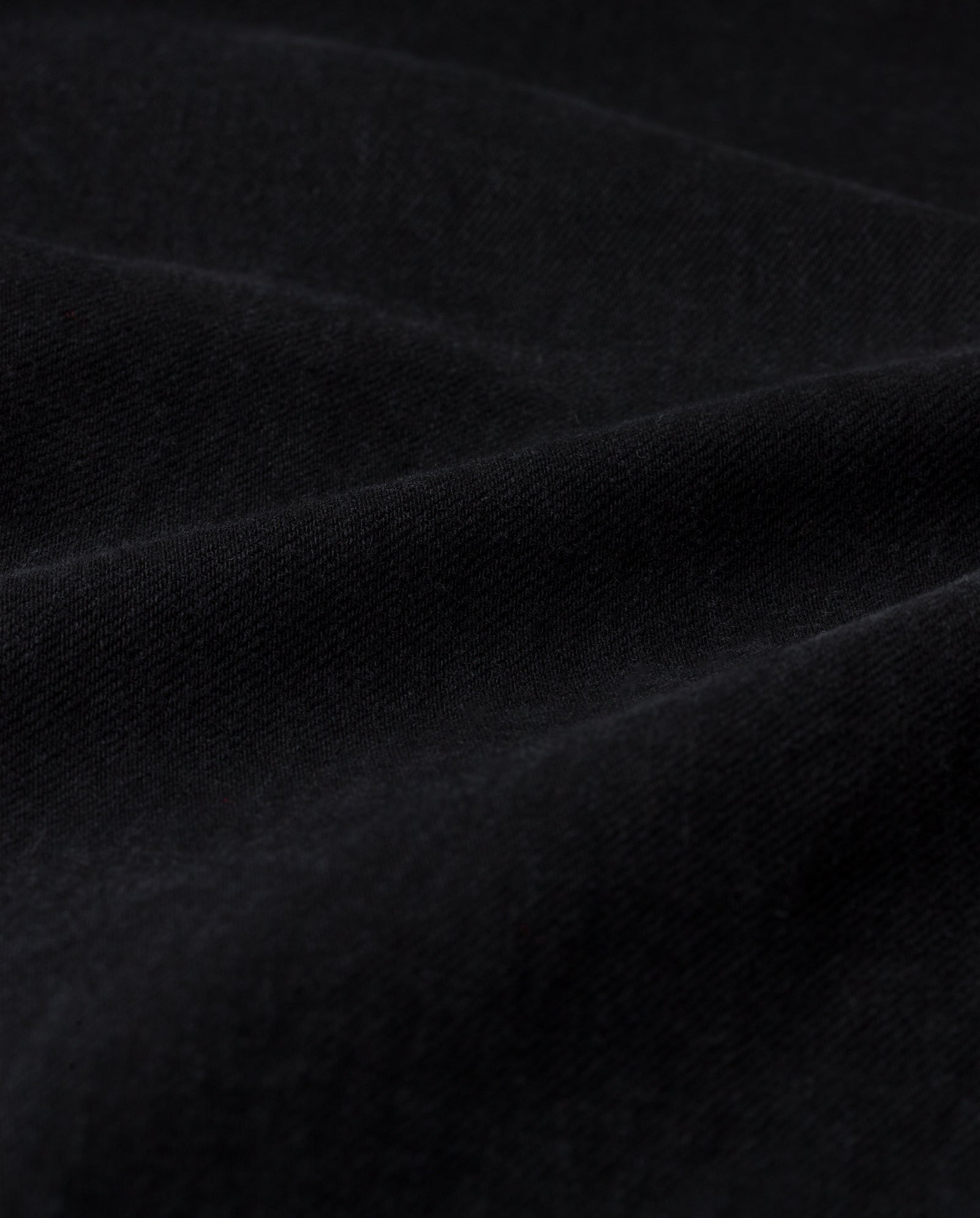 Close-up of soft black fabric with gentle, wavy folds and a textured surface, reminiscent of the drape found in IVY OAKs PRIJANKA Trousers.