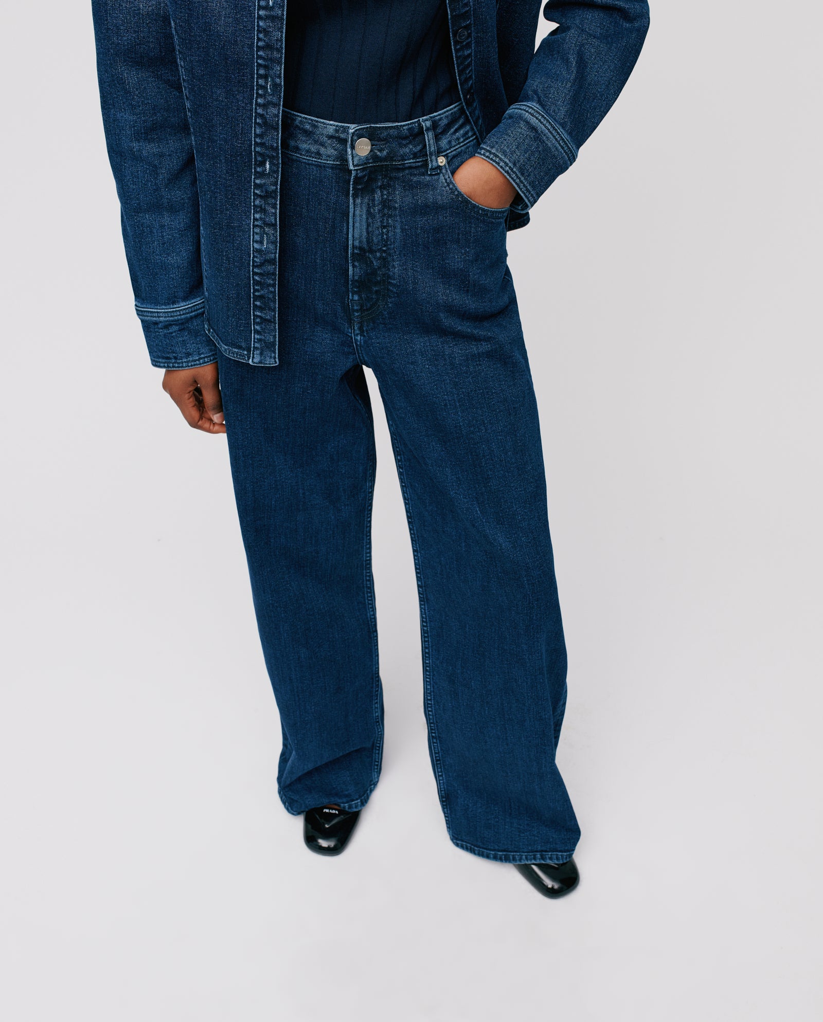 Wearing IVY OAKs PRIJANKA Trousers—high-waisted with a wide, loose leg—paired with a rich indigo denim jacket and black shoes, one hand casually in the pocket.