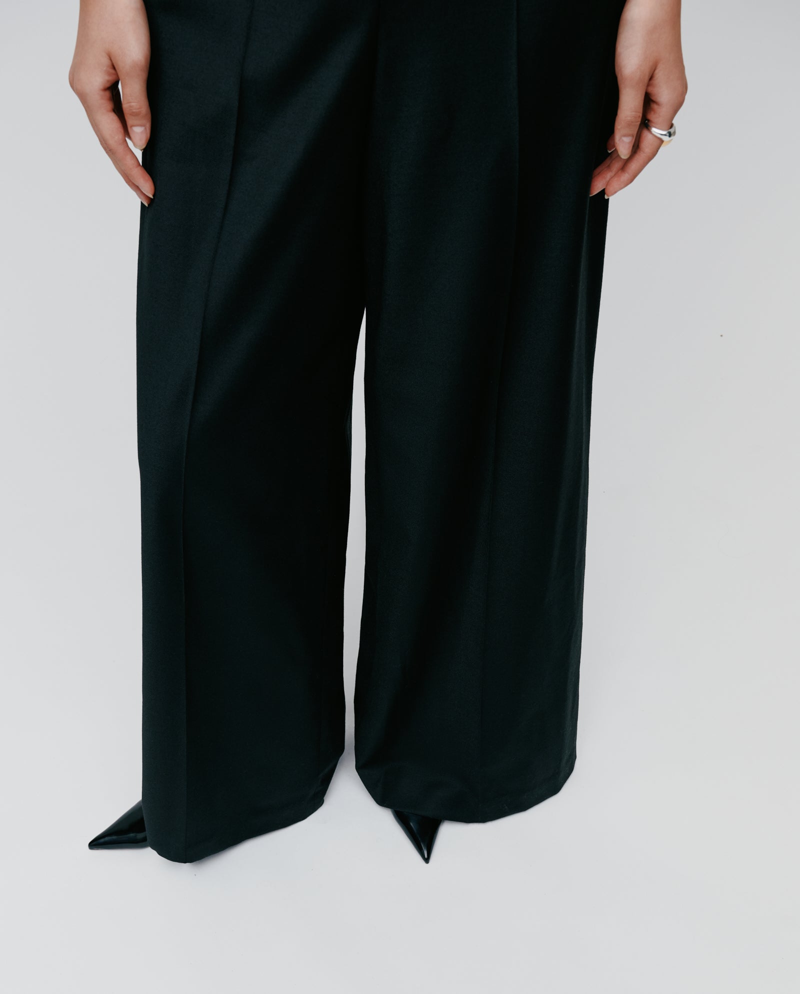 A person stands on a light background wearing the IVY OAK PEPPINA Jumpsuit in black with black pointed-toe shoes.