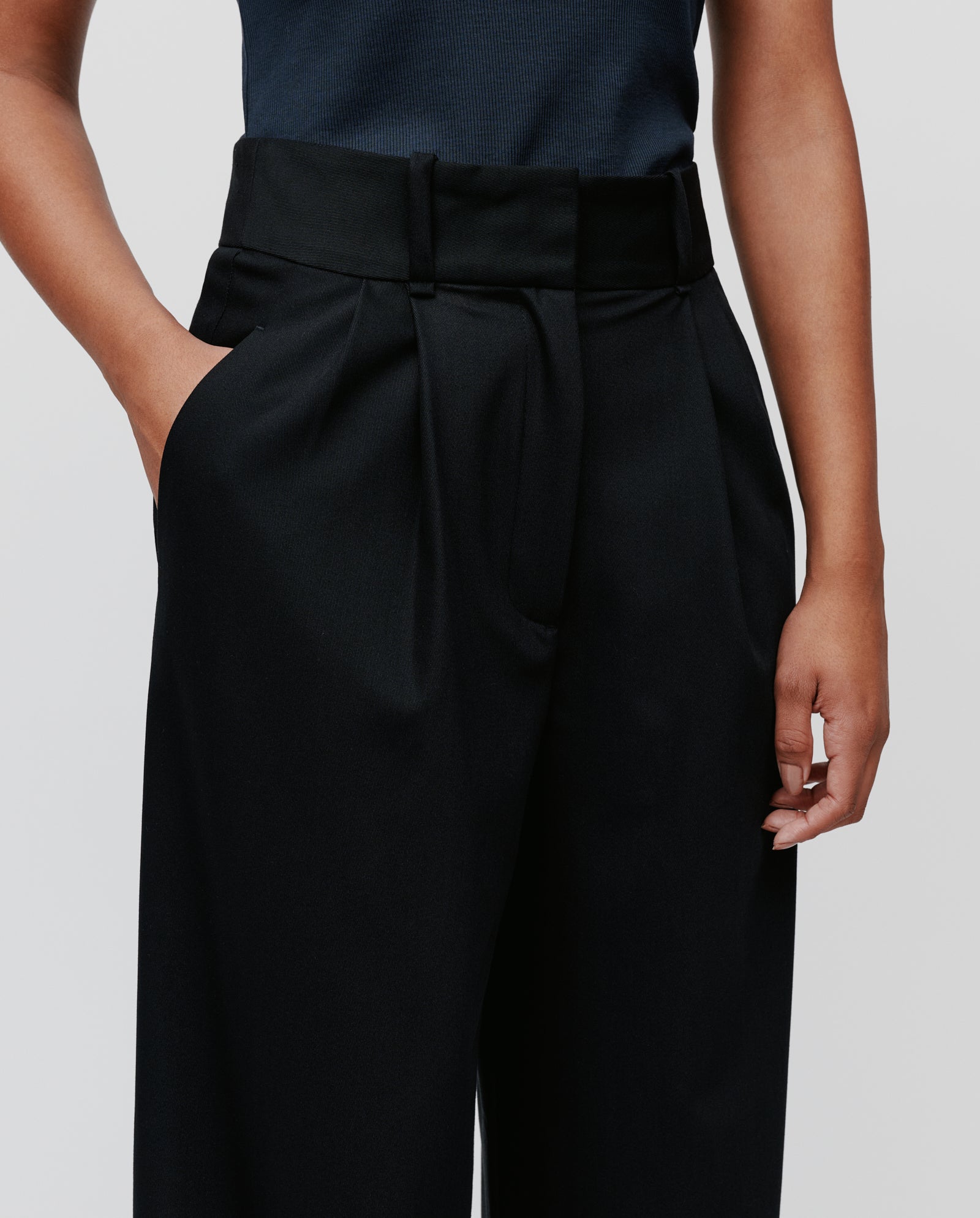 A person models the IVY OAK PRESCILLIA ANN Trousers—chic, high-waisted with French pockets—one hand casually in their pocket, set against a plain background.