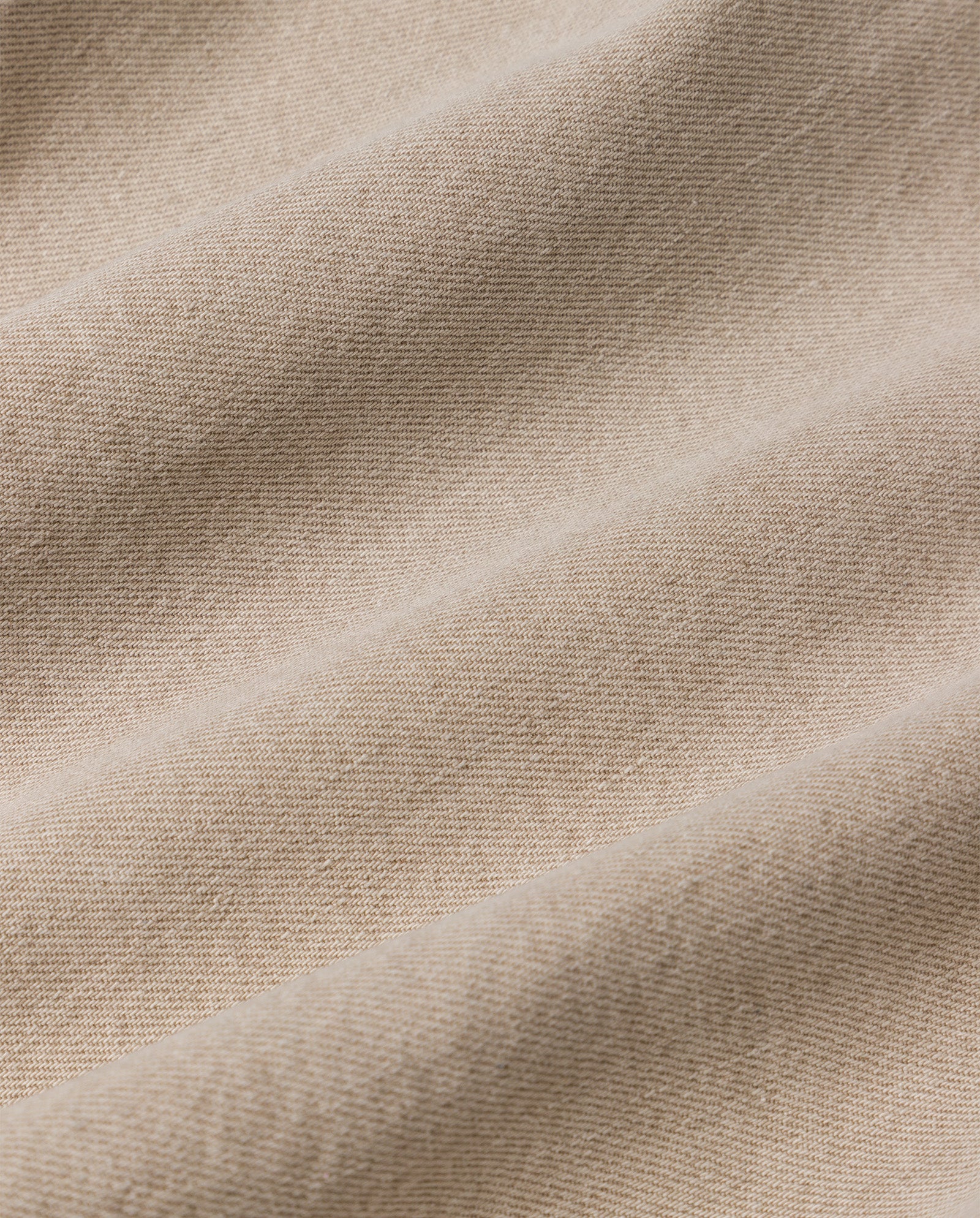 Close-up of beige textured fabric with diagonal folds, perfect for crafting the PRIJANKA Jeans by IVY OAK—high-waisted, indigo denim jeans with a loose wide-leg silhouette.