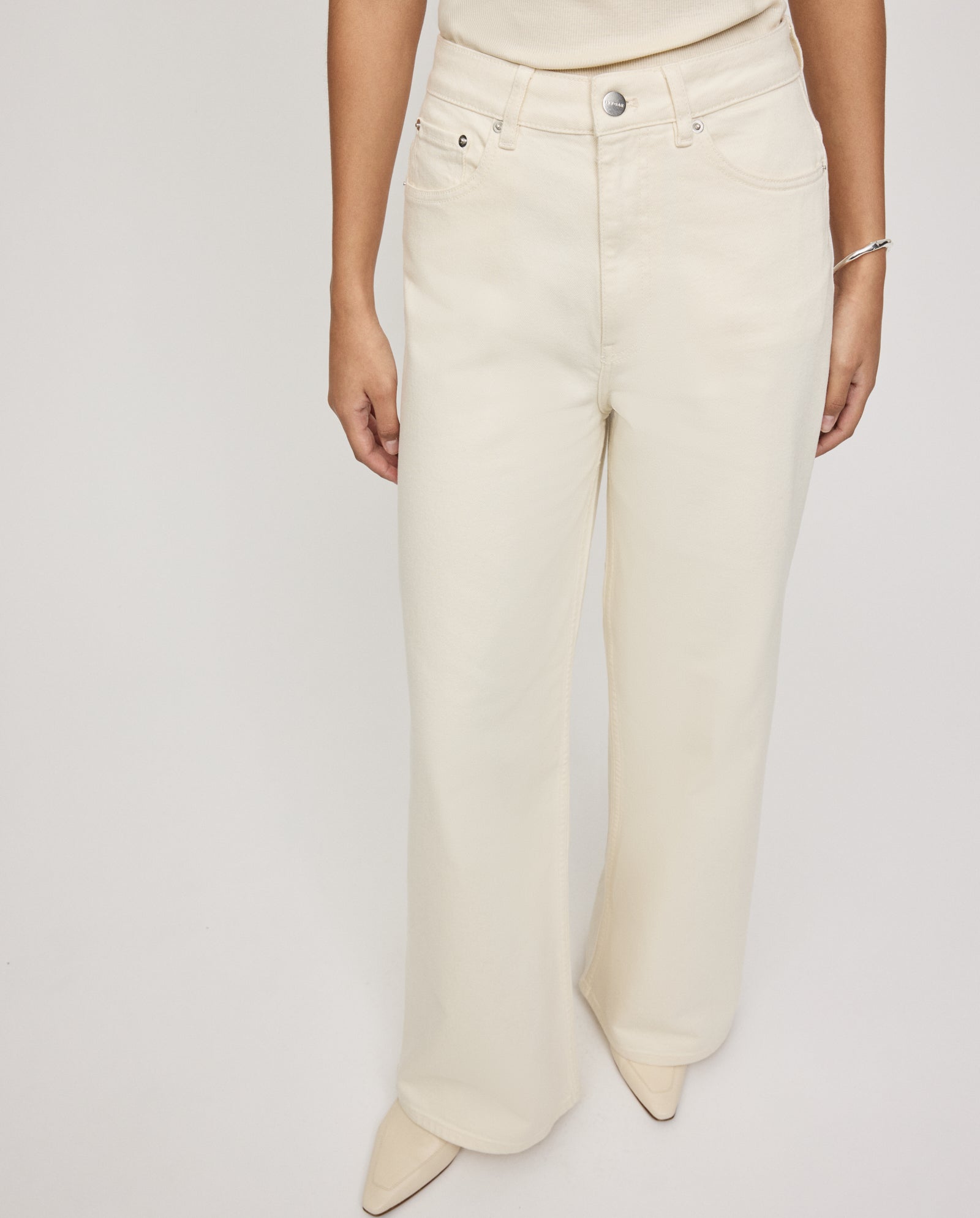 A person wears IVY OAK’s PRIJANKA Jeans—high-waisted, loose, wide-leg denim—styled with a light top and pointed-toe shoes.