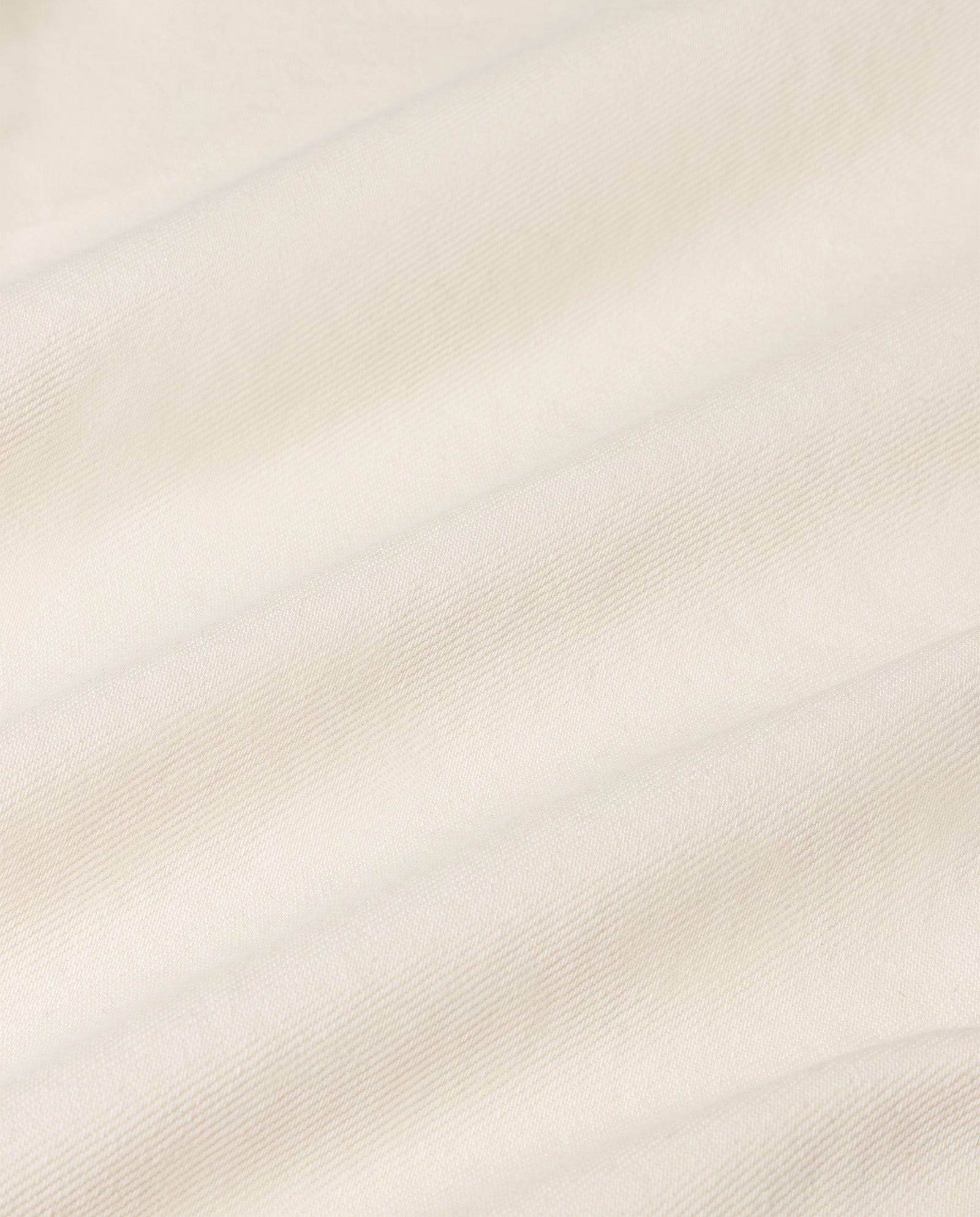 Cream-colored fabric featuring soft diagonal folds and a subtle texture—ideal for styling with IVY OAK’s PRIJANKA Jeans, a high-waisted, indigo pair of loose, wide-leg denim.