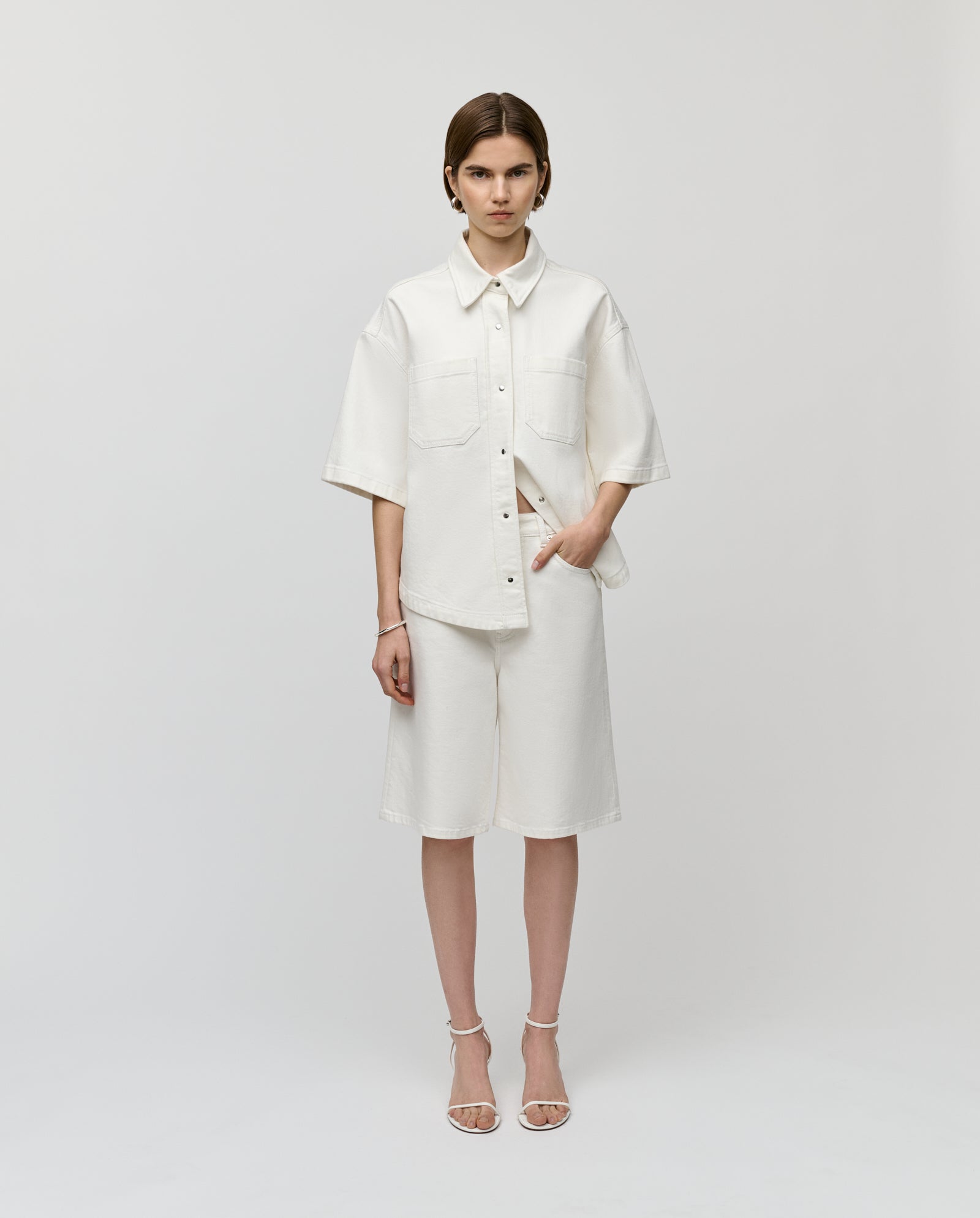 Woman wearing IVY OAKs PIRI Pants with a loose white button-up shirt, standing against a plain background.