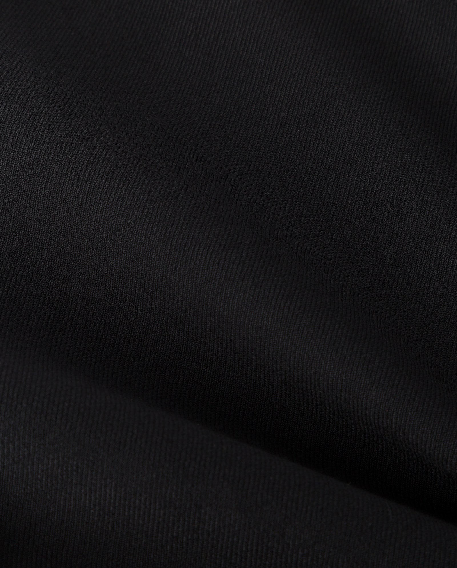 Close-up of black fabric with visible texture and light folds, highlighting the refined finish of IVY OAK’s PRESCILLIA SUE Pants.