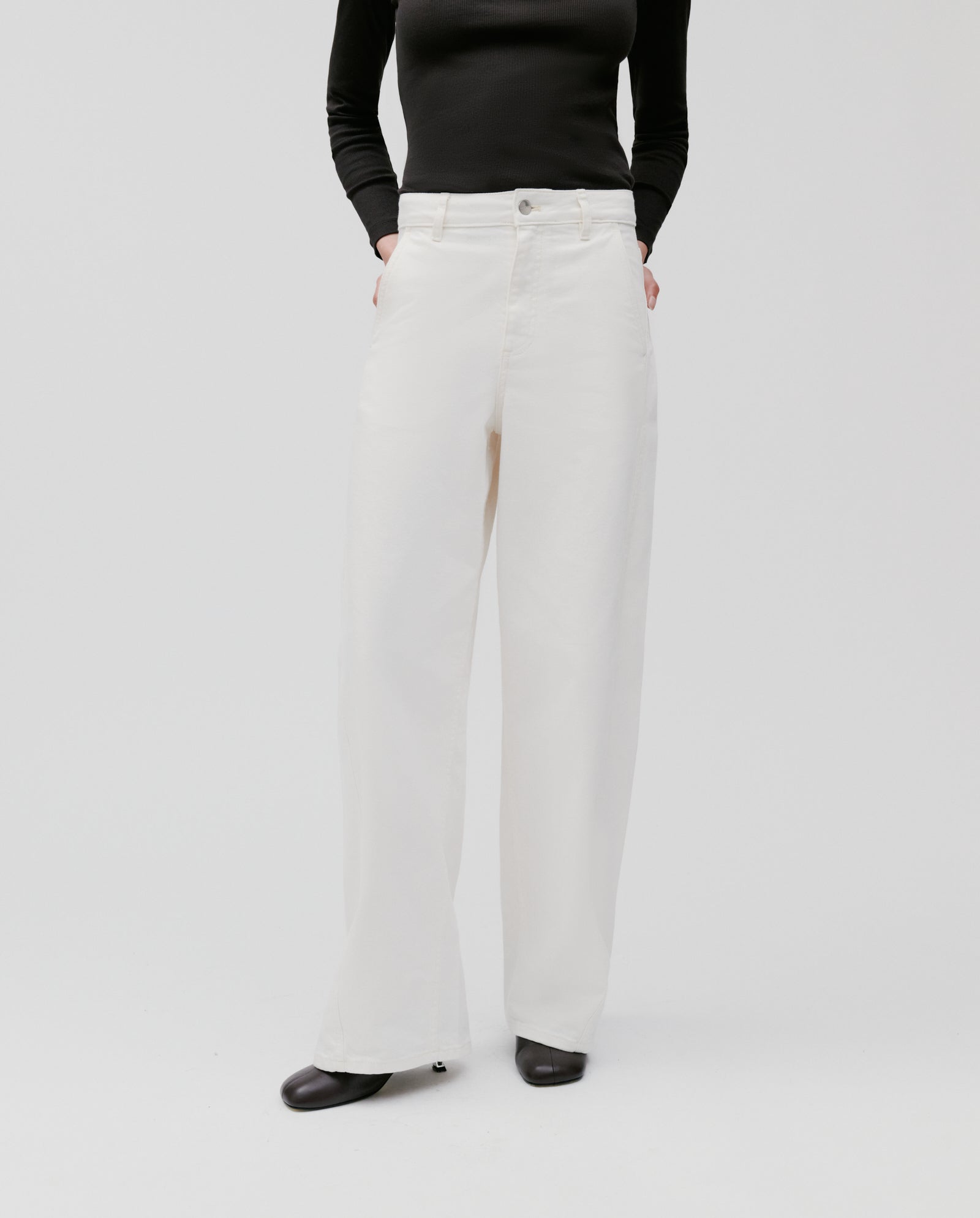 Person wearing IVY OAK’s PHILA Pants, styled with a black long-sleeve top and black shoes, hands in pockets.