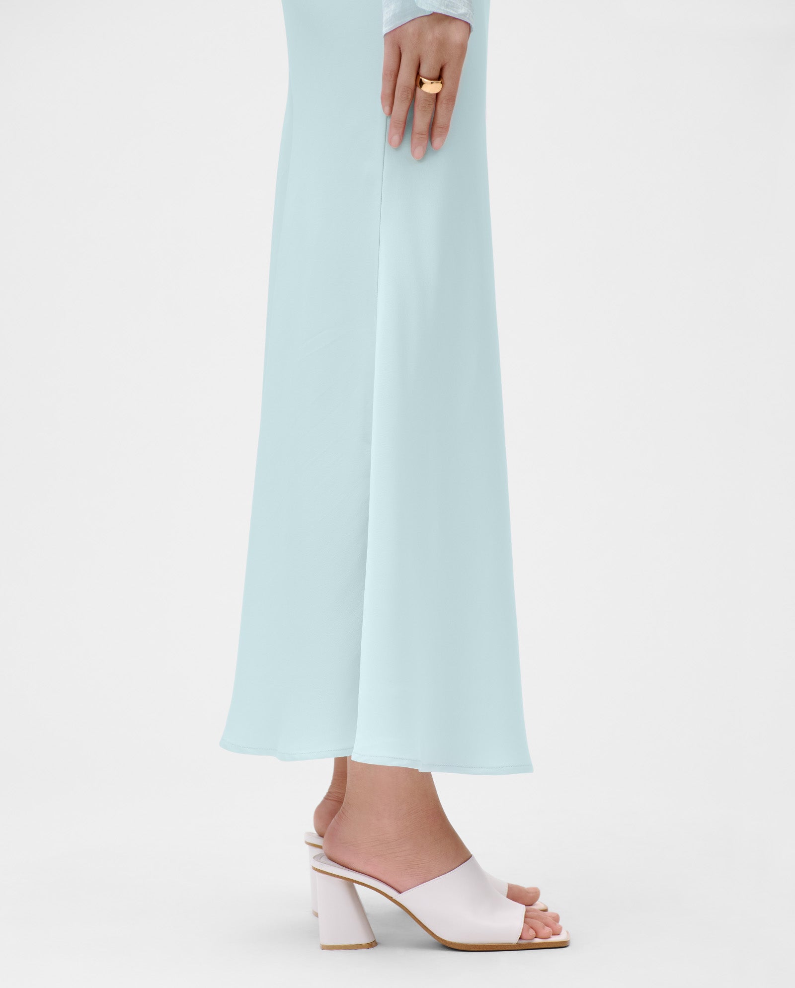 Woman in the IVY OAK SUMMER Skirt, paired with white heeled sandals and a gold ring.