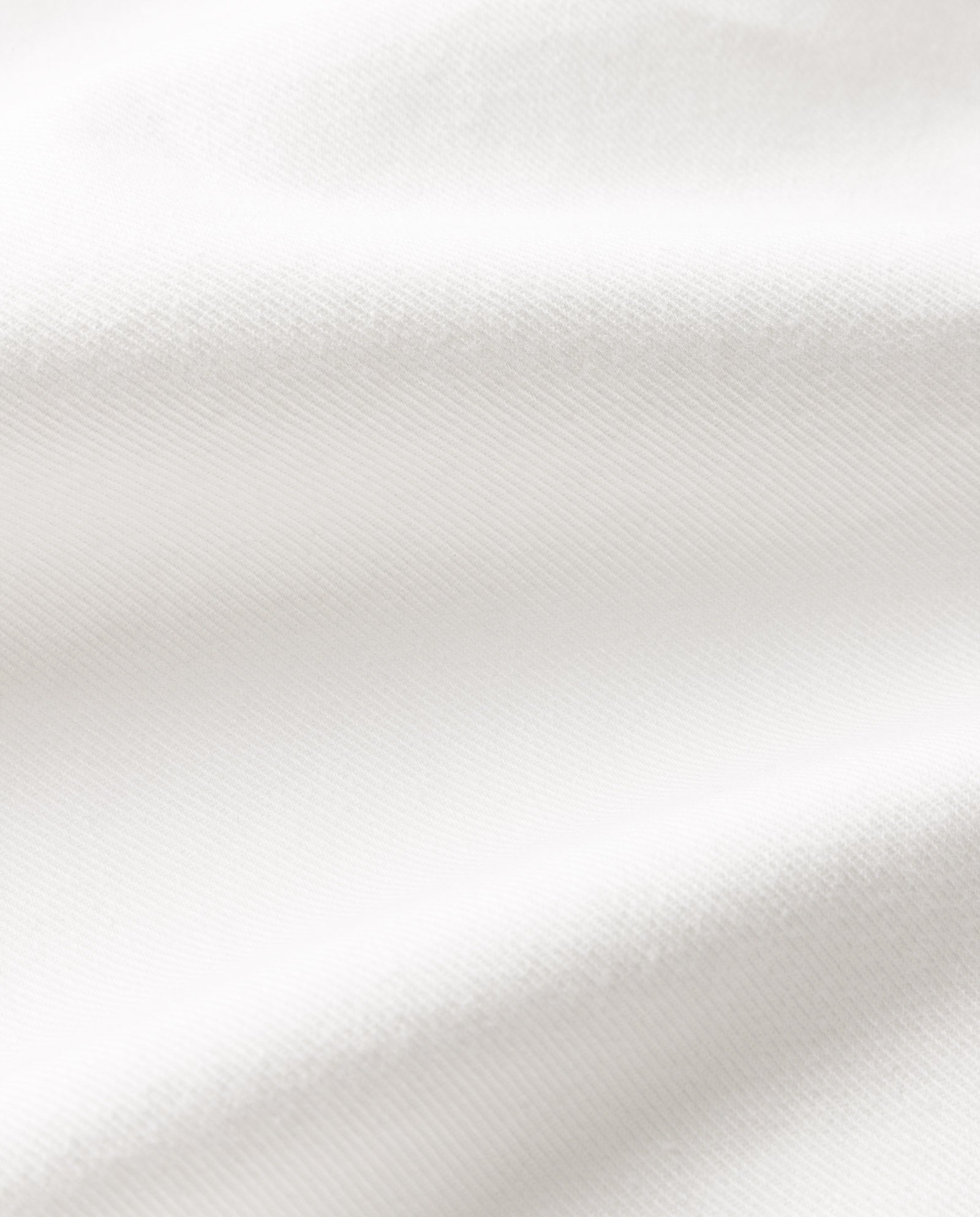 Close-up of white fabric with soft folds and a subtle diagonal texture, as seen in the IVY OAK STEFANIE Skirt.