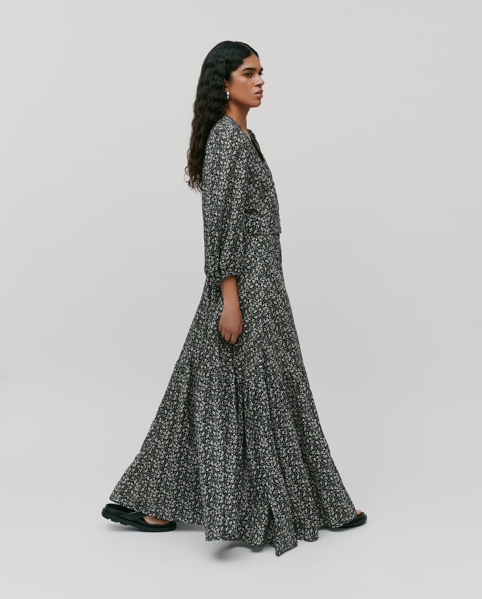 Model wears the IVY OAK SANJA Skirt, a long, flowy black and white patterned piece with an elastic waistband, paired with black shoes against a plain background.