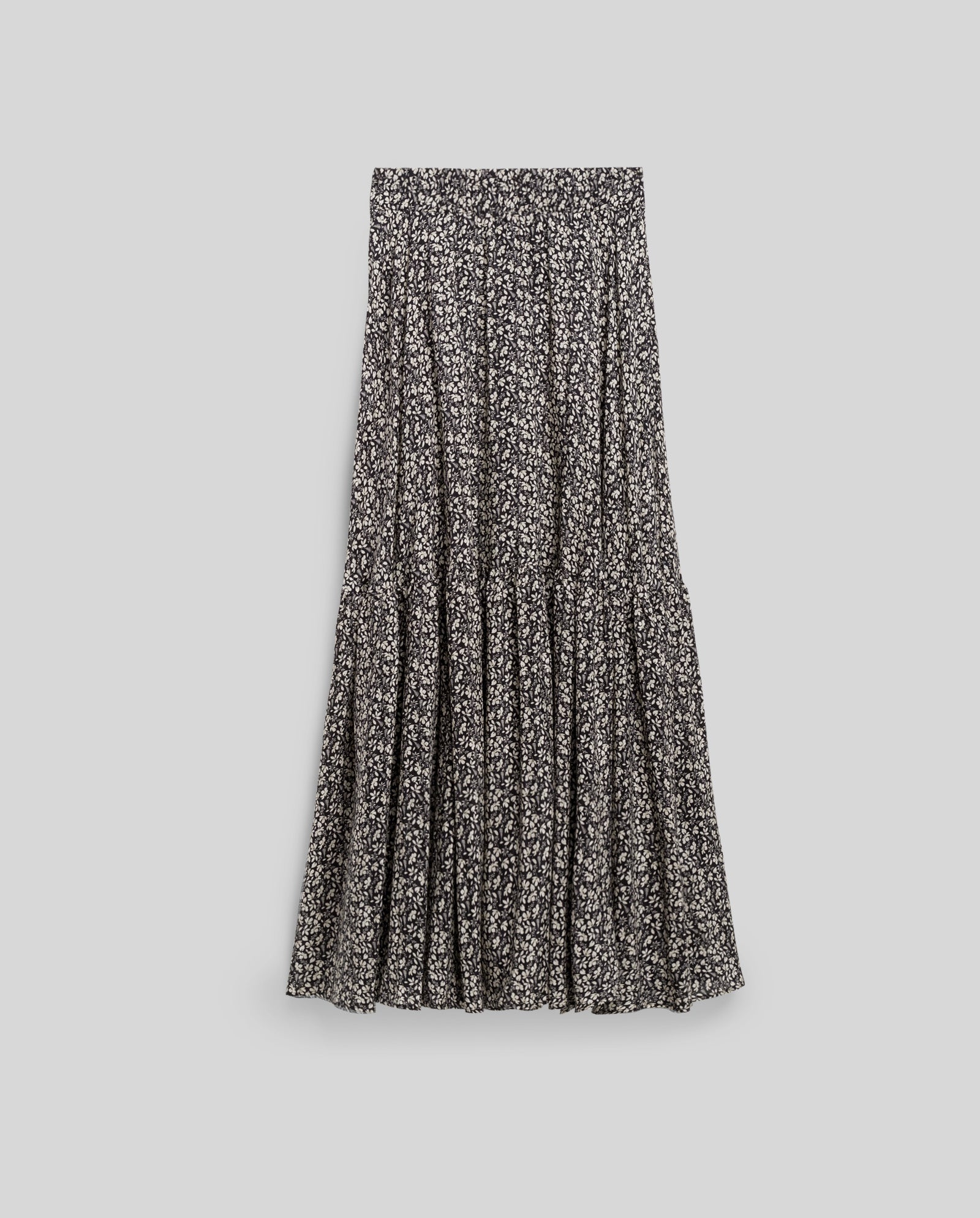 The IVY OAK SANJA Skirt is a black and white floral maxi with a tiered, flowy design and an elastic waistband, shown on a plain gray background.
