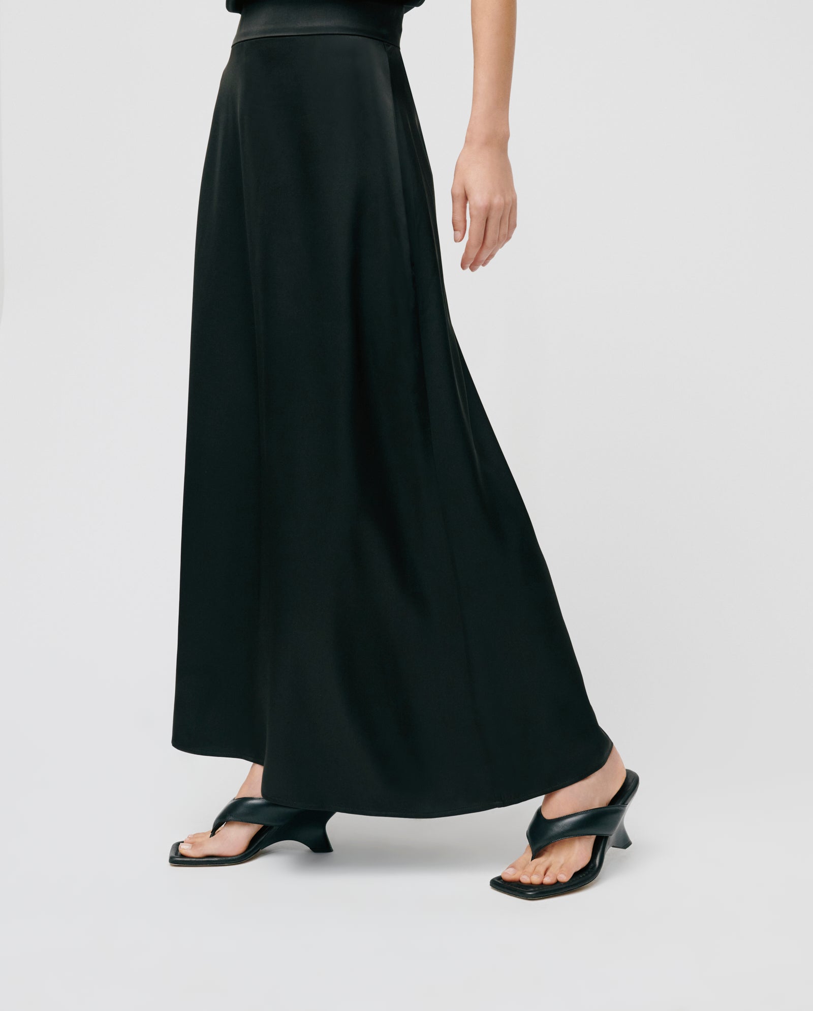 A person wears an ankle-length IVY OAK SANNA Skirt made from NAIA acetate with black heeled sandals, standing against a plain white background.
