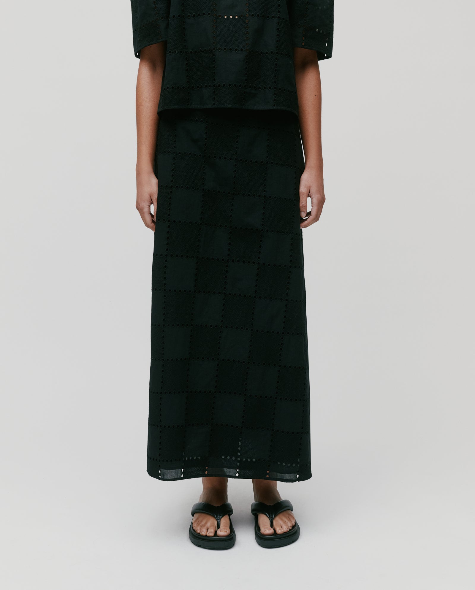 A person wearing the IVY OAK SAMANTHA Skirt with a back zipper closure, paired with a matching top and black sandals, stands against a plain background.