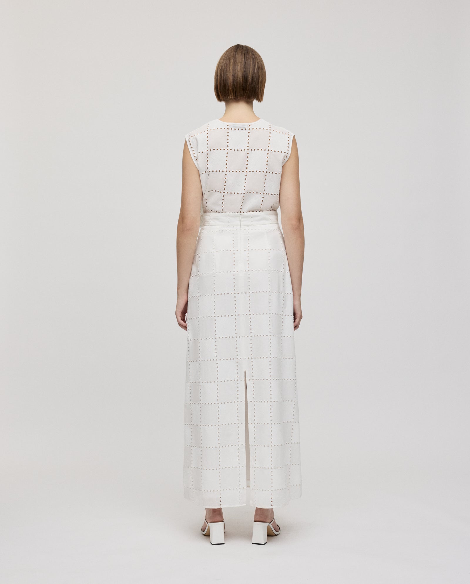 Person with short hair wears the IVY OAK SAMANTHA Skirt and white shoes, standing with back to the camera.