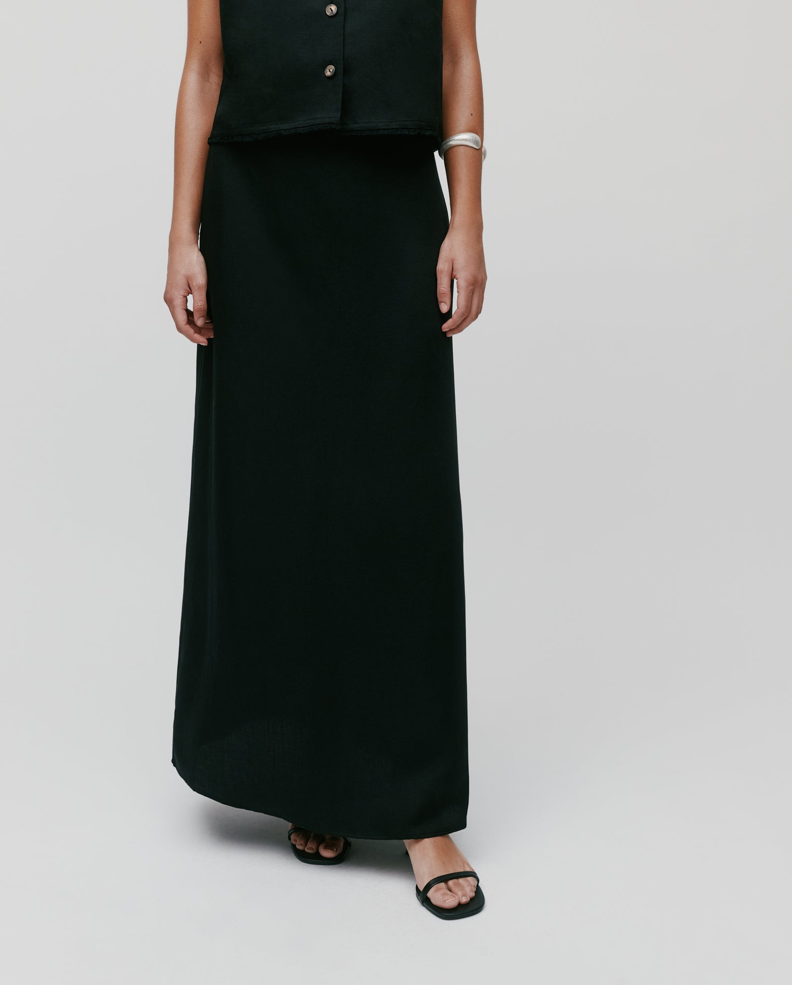 A person wears the IVY OAK SAMANTHA ANN Skirt with a black sleeveless top and black sandals, set against a plain background.