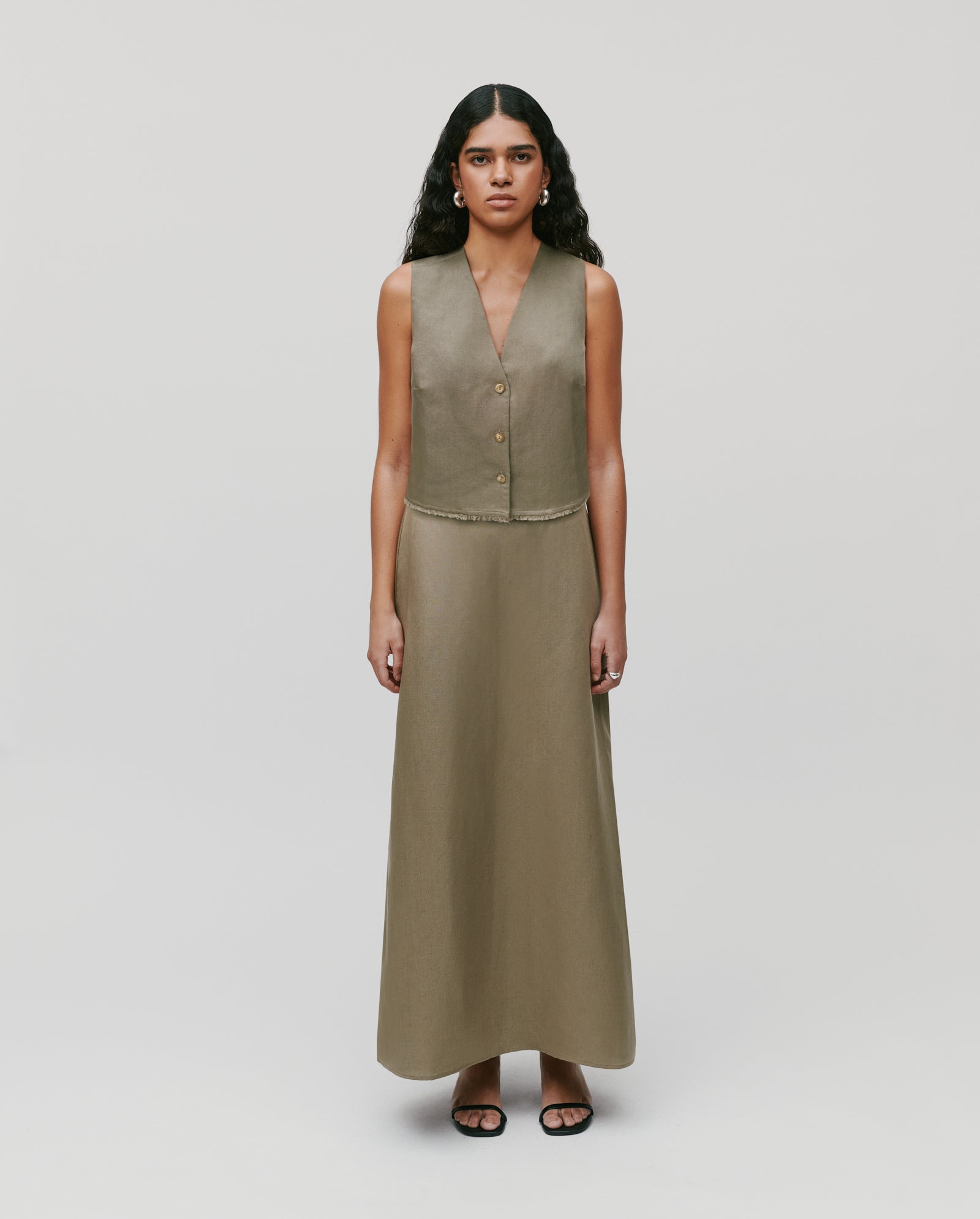 Woman in a sleeveless, light brown vest and IVY OAK SAMANTHA ANN Skirt stands against a plain background.