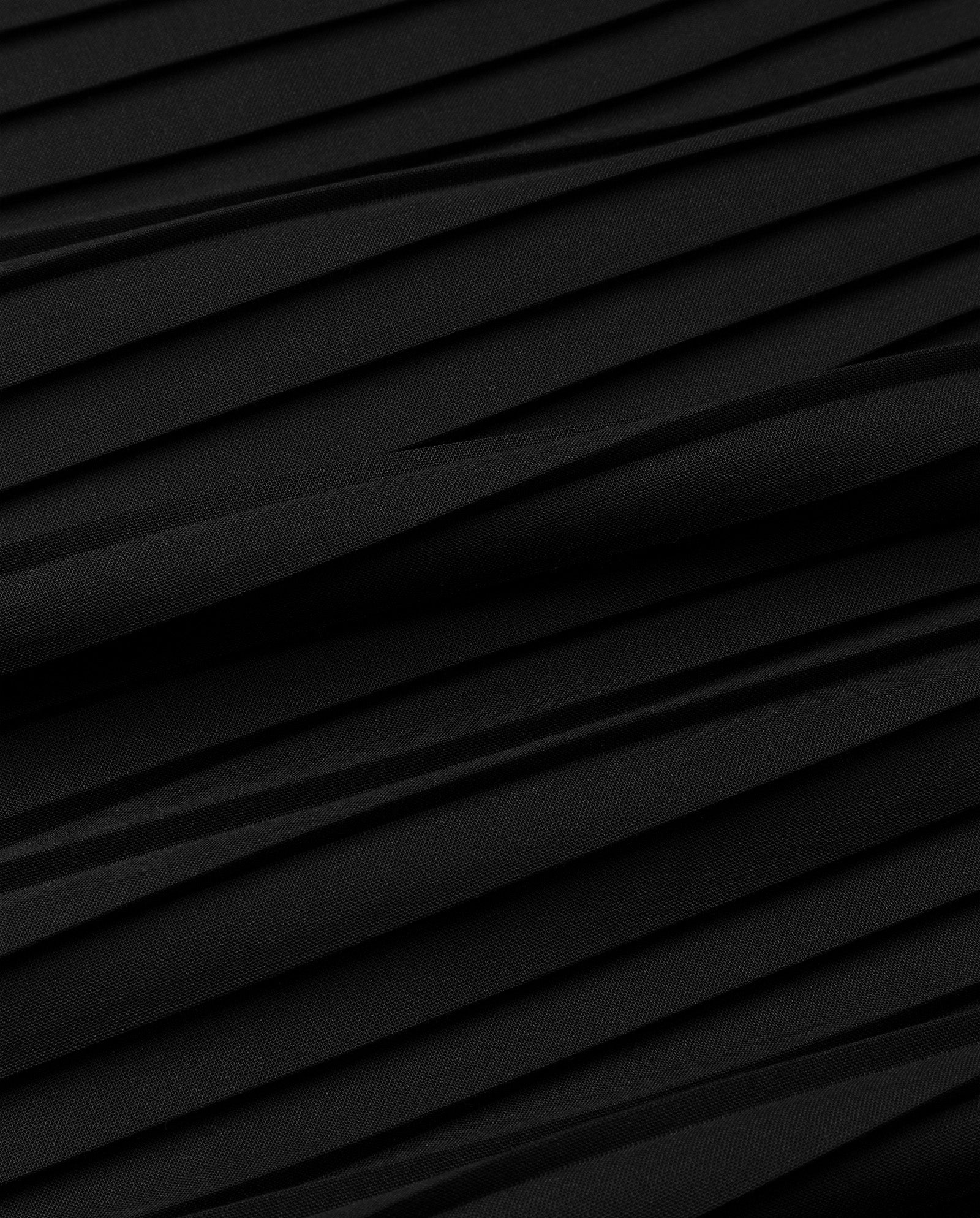 Close-up of the IVY OAK SALENA Skirt in black, showcasing its luxurious plissé fabric with diagonal folds that create rich texture and depth.