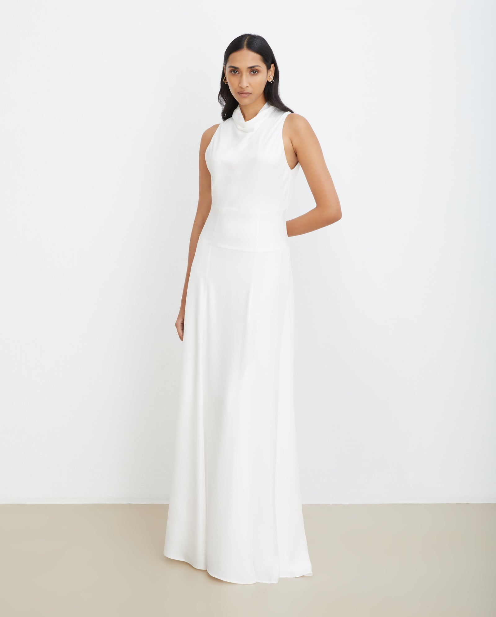 A woman wearing the IVY OAK NABINA LOU Bridal Dress—sleeveless, floor-length, A-line with a waterfall collar—stands against a plain white background.