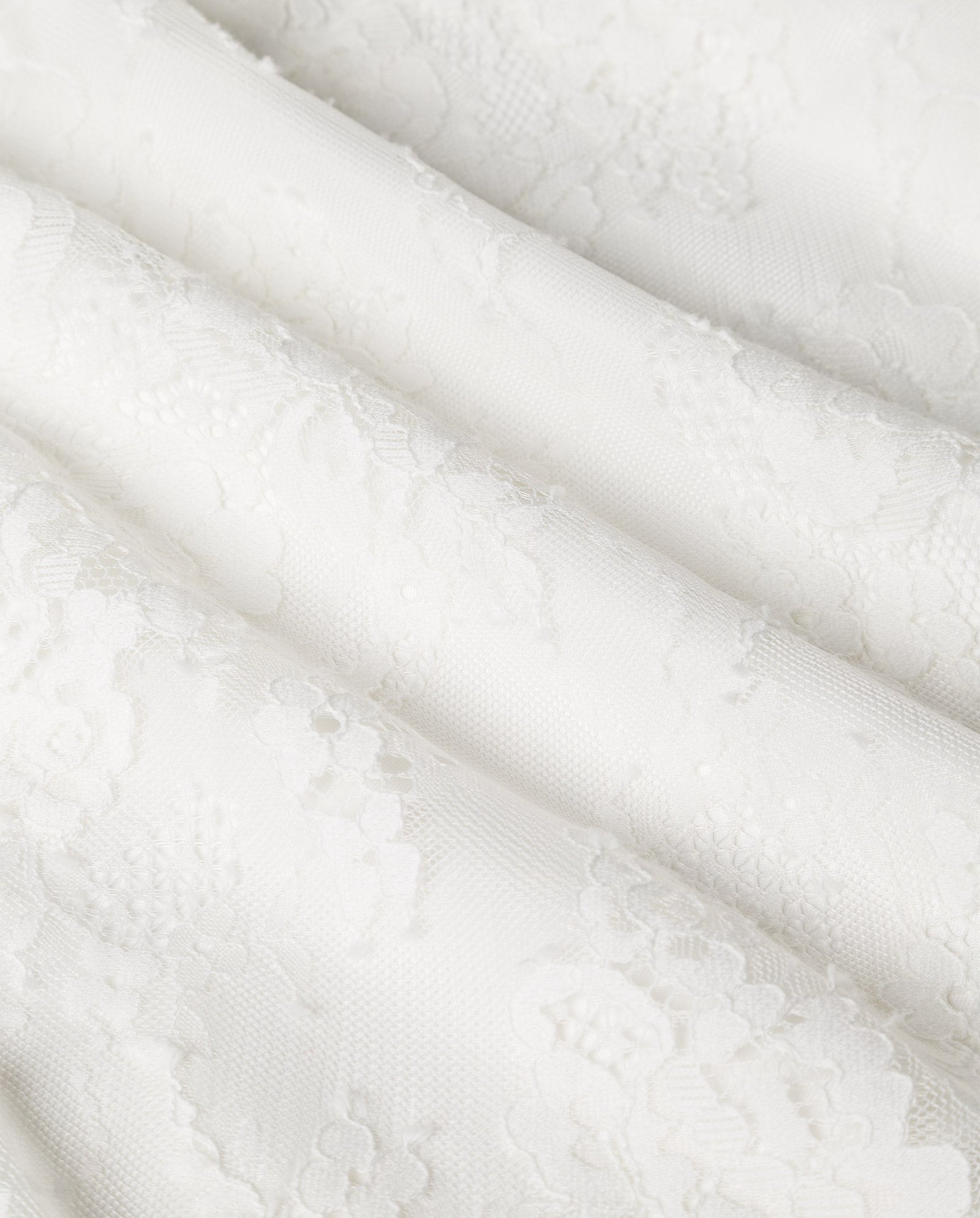 The MARCITA Bridaldress by IVY OAK features white lace with a delicate floral pattern and flowing folds, ideal for a maxi-length wedding dress with a scalloped hem.