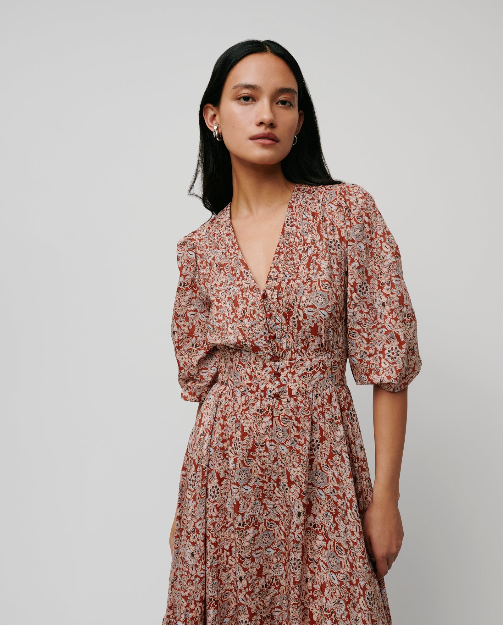 A woman wearing the IVY OAK DREA Dress with red and white floral print, puff sleeves, and a V-neck stands against a plain background.
