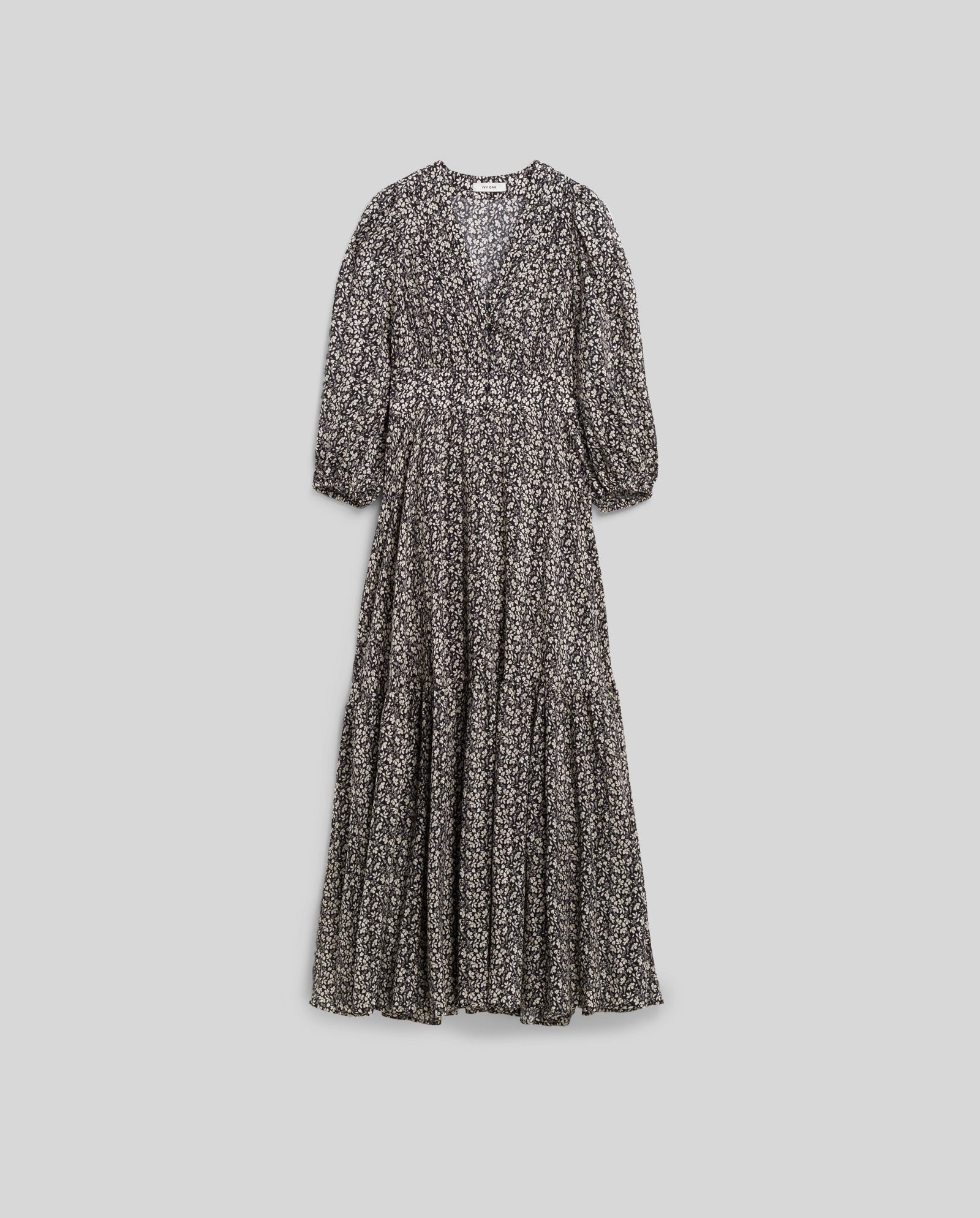 The IVY OAK DREA Dress is a black, long-sleeved maxi dress with a white floral pattern, V-neckline, and gathered waist for a flattering silhouette.