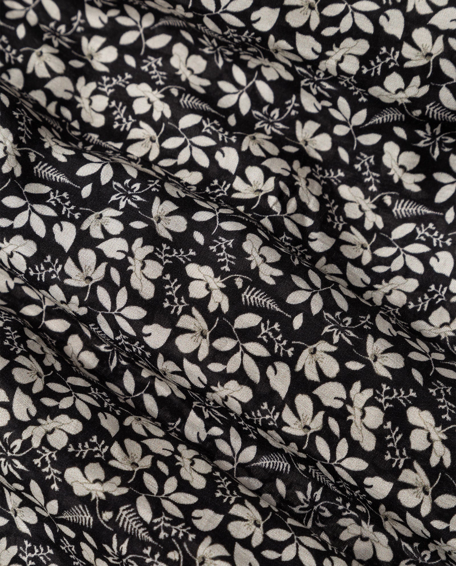 The IVY OAK DREA Dress features black fabric with small white floral and leaf patterns, gathered in gentle folds and designed with a flattering V-neck.