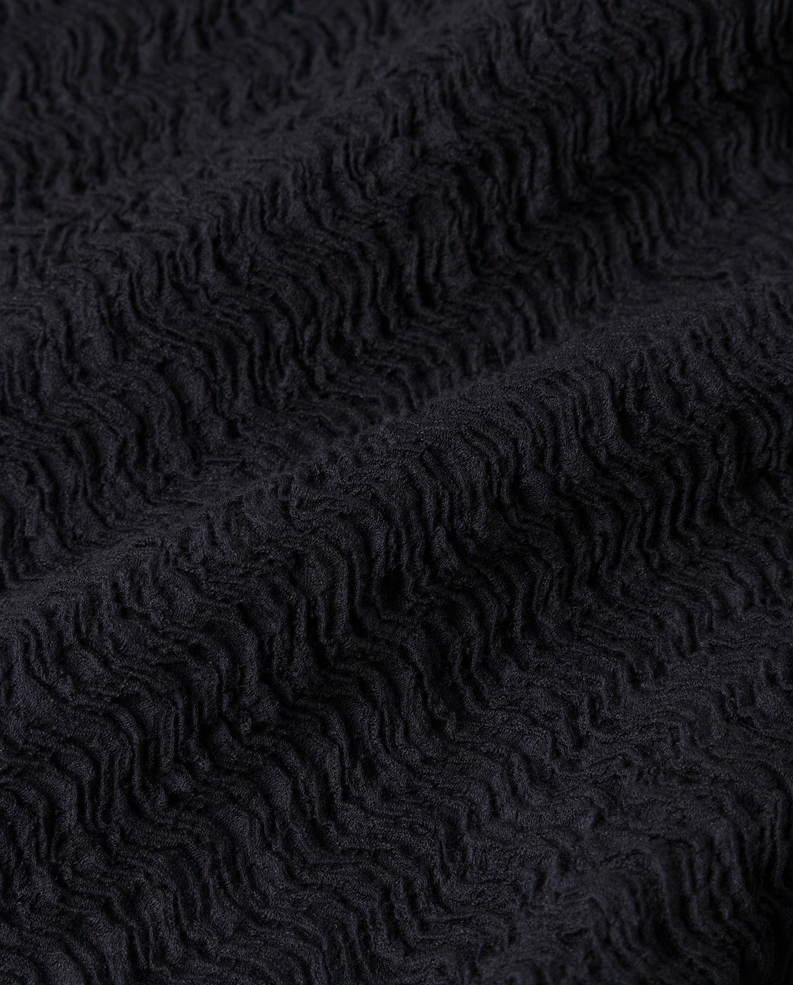Close-up of black textured fabric with a wavy, raised pattern and soft look—perfect for the IVY OAK MARCELLA Dress, an elegant ankle-length style.
