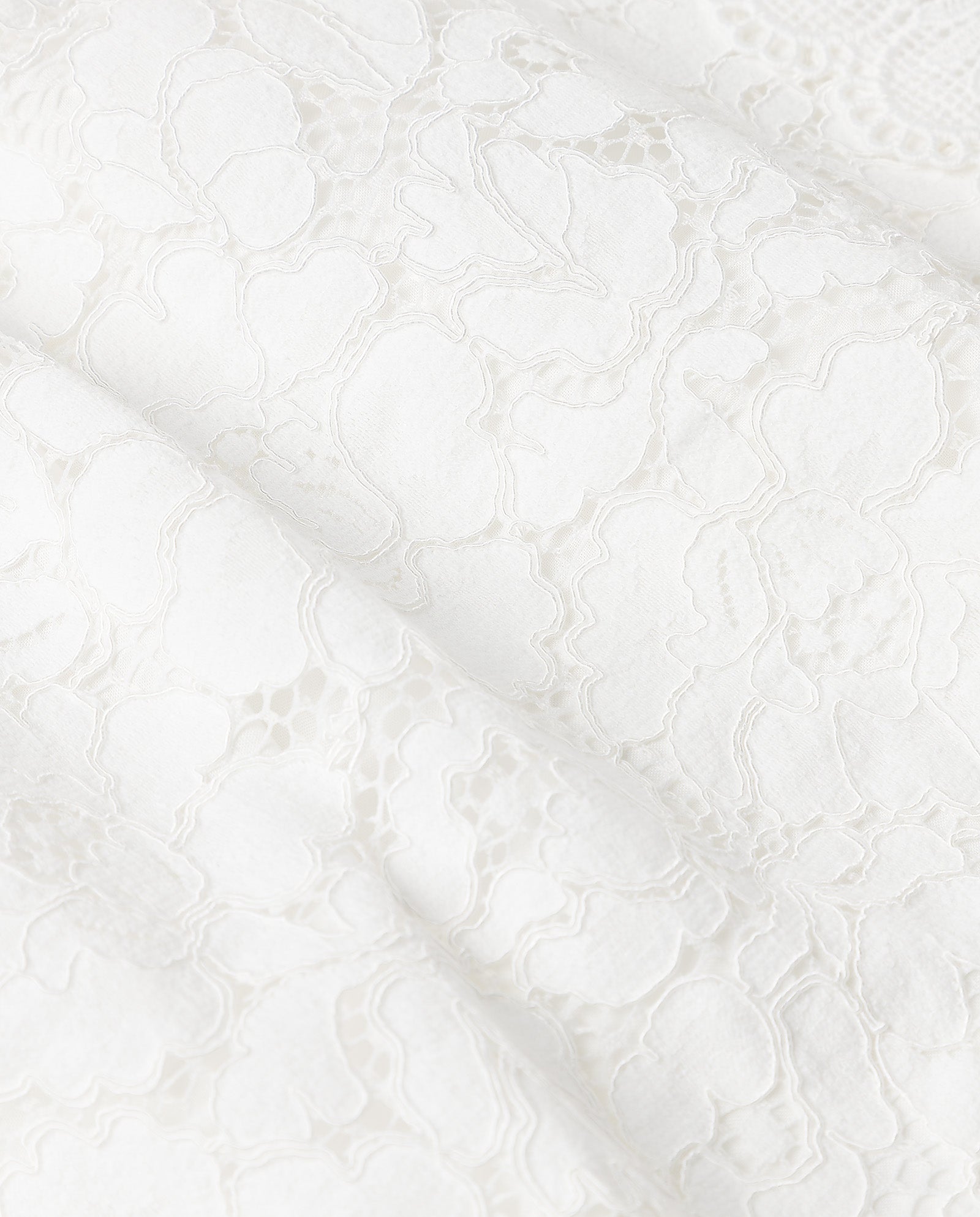 Close-up of NYNA ROSE Bridaldress by IVY OAK, featuring white floral lace with intricate patterns and a delicate, semi-transparent texture—ideal for a chic midi length wedding dress.