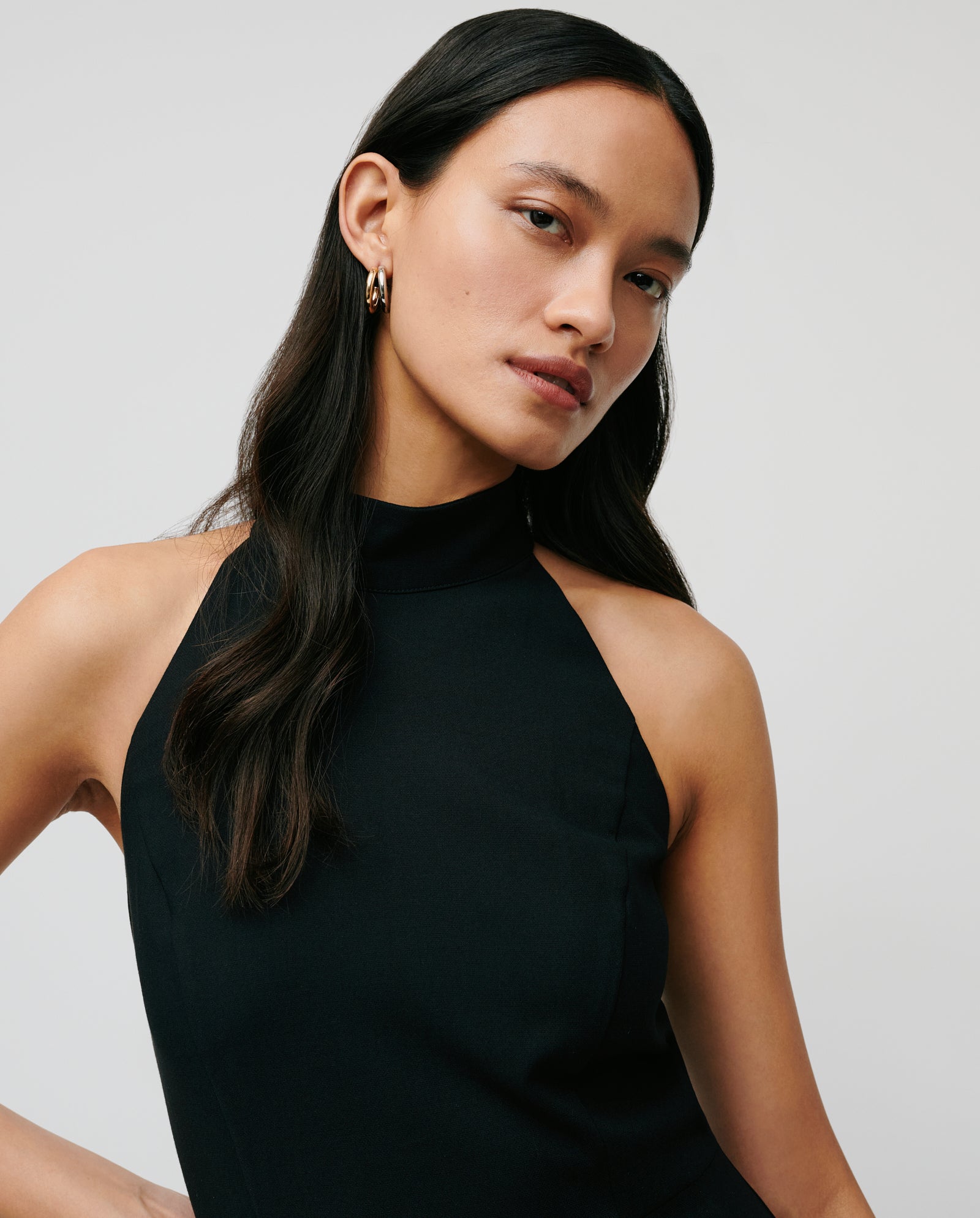 Woman with long dark hair wears the IVY OAK NOLAN Dress—a sleeveless, black, body-hugging neckholder—while looking at the camera against a plain background.